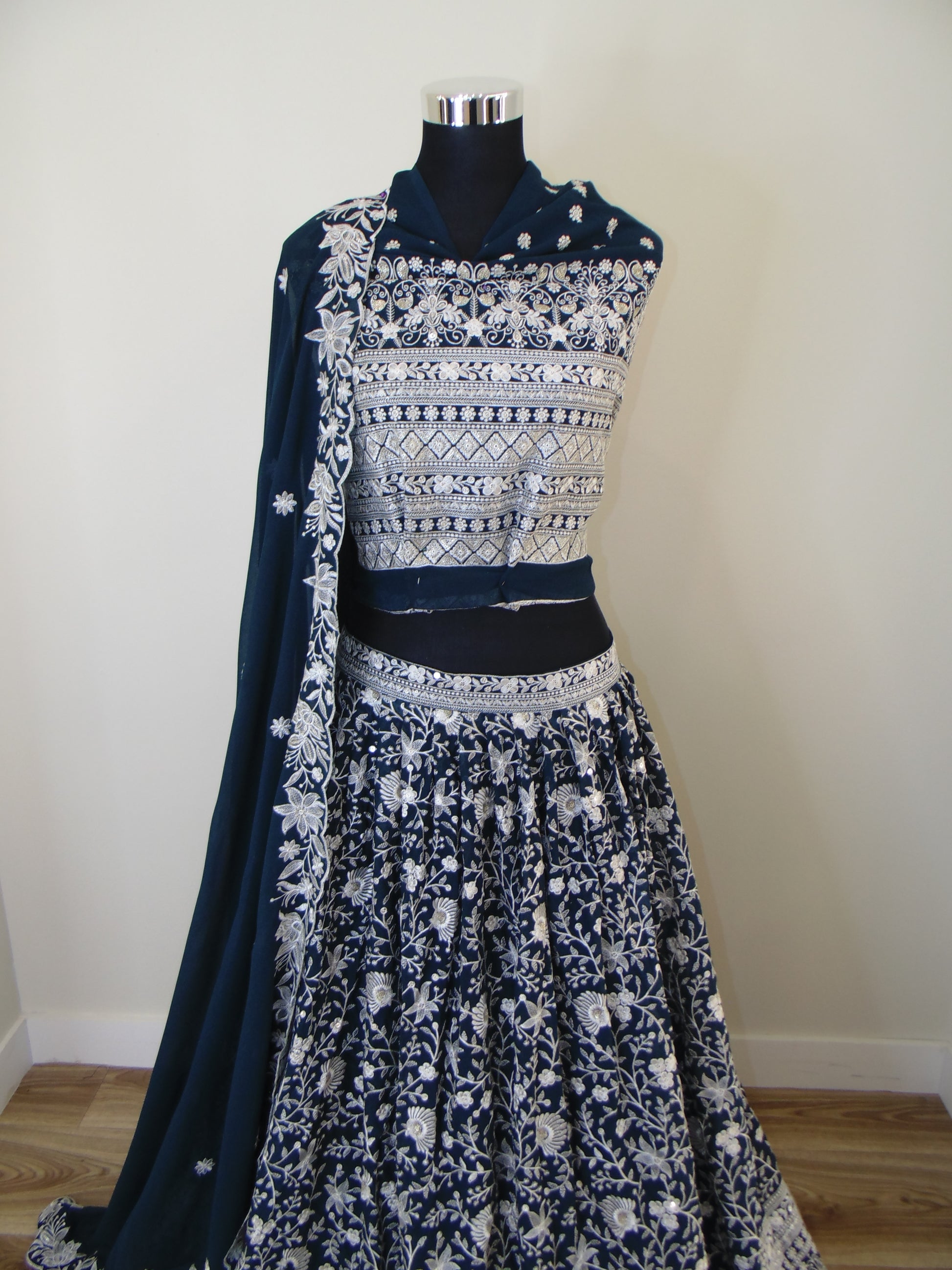 Navy blue dress with white floral patterns on a mannequin against a plain background