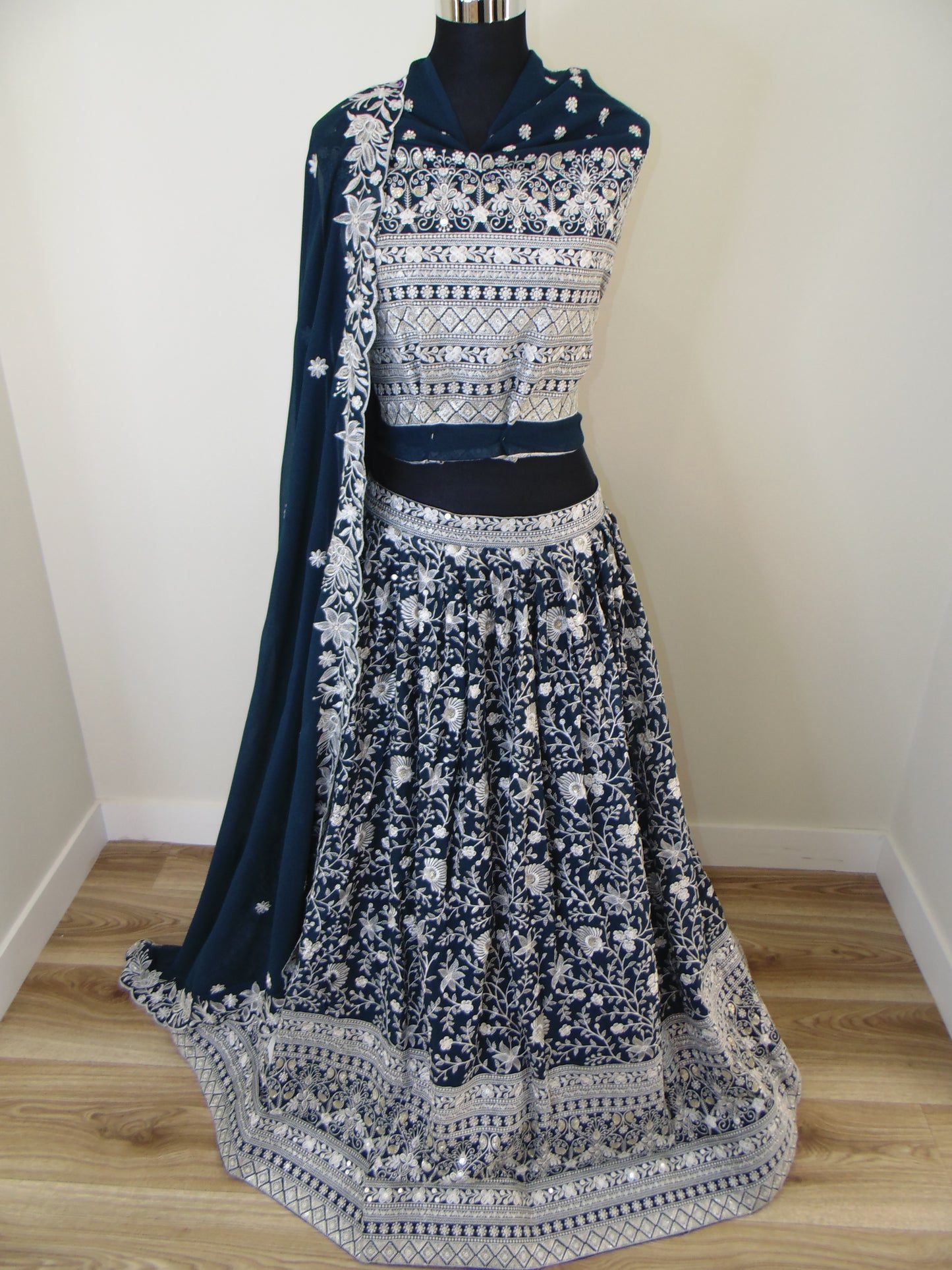 Black and white patterned Indian Lehenga on a hanger against a neutral wall.