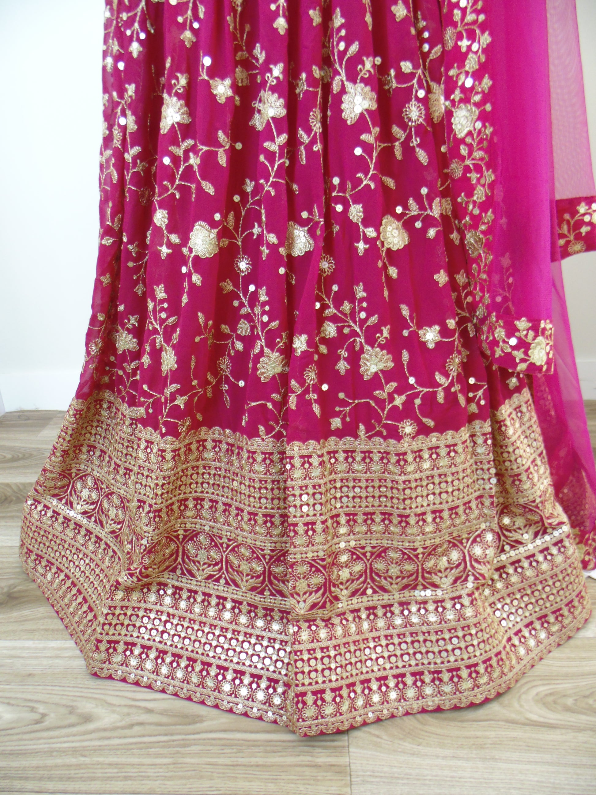 Pink Lehenga with gold embroidery on a wooden surface