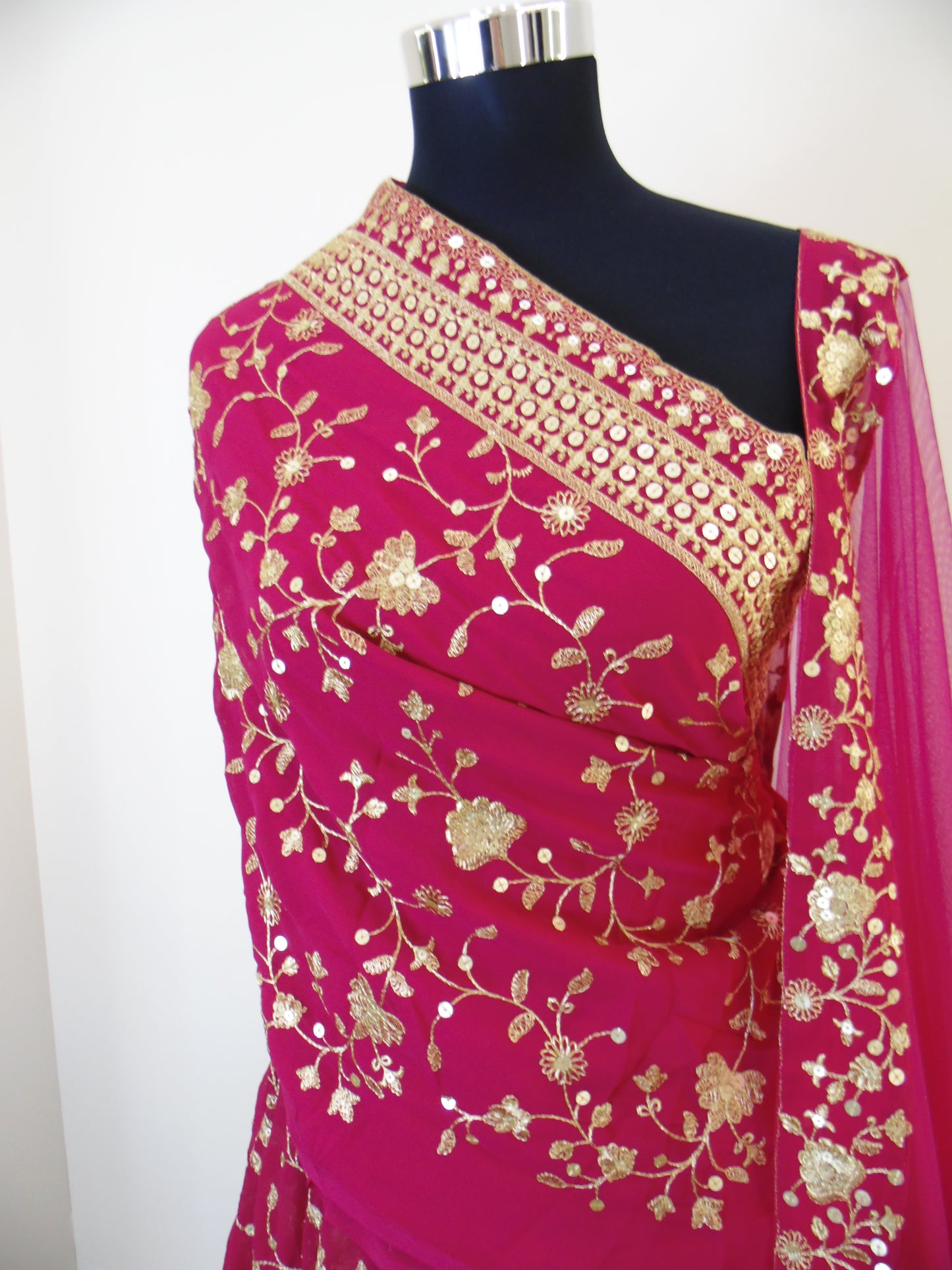 Pink saree with gold floral embroidery on a white background