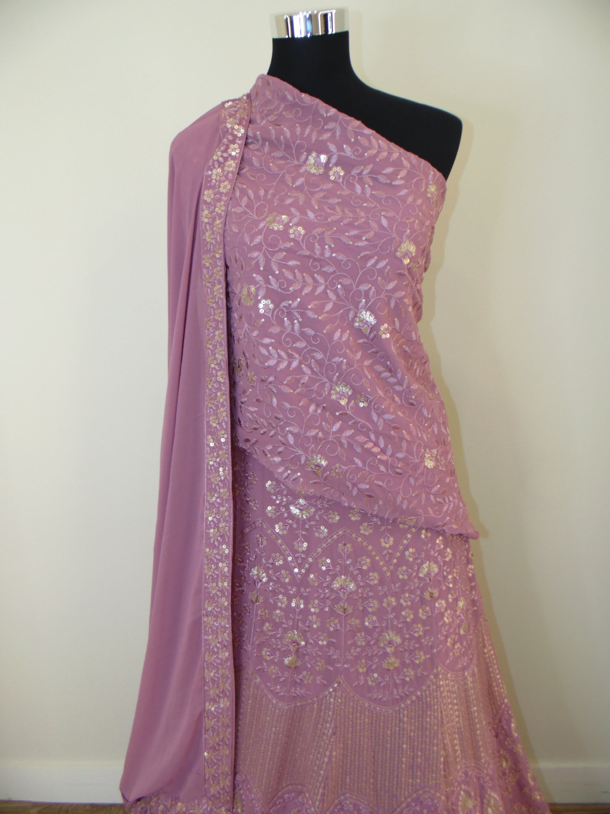 Pink embroidered fabric on a mannequin against a white background