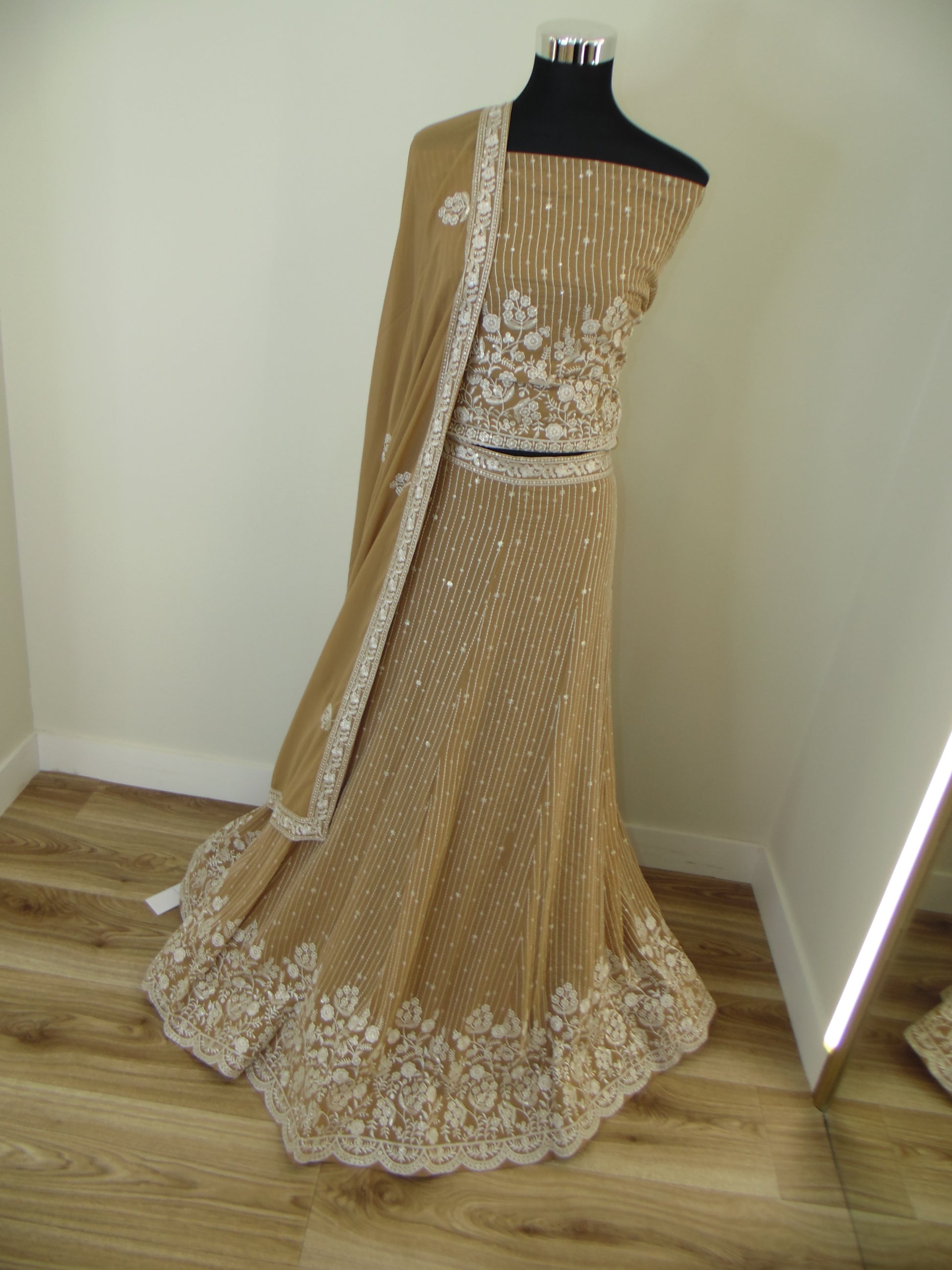 Gold embroidered dress on a mannequin against a neutral background