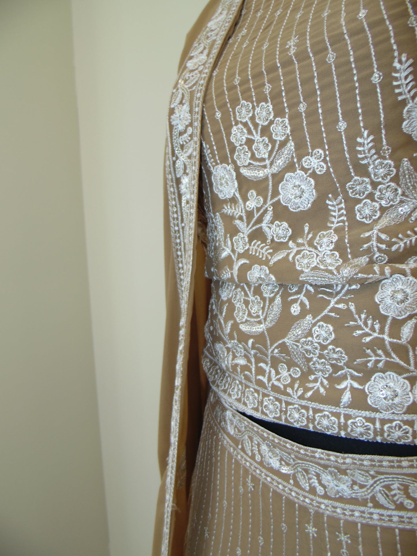 Brown fabric with white floral embroidery on a beige background
