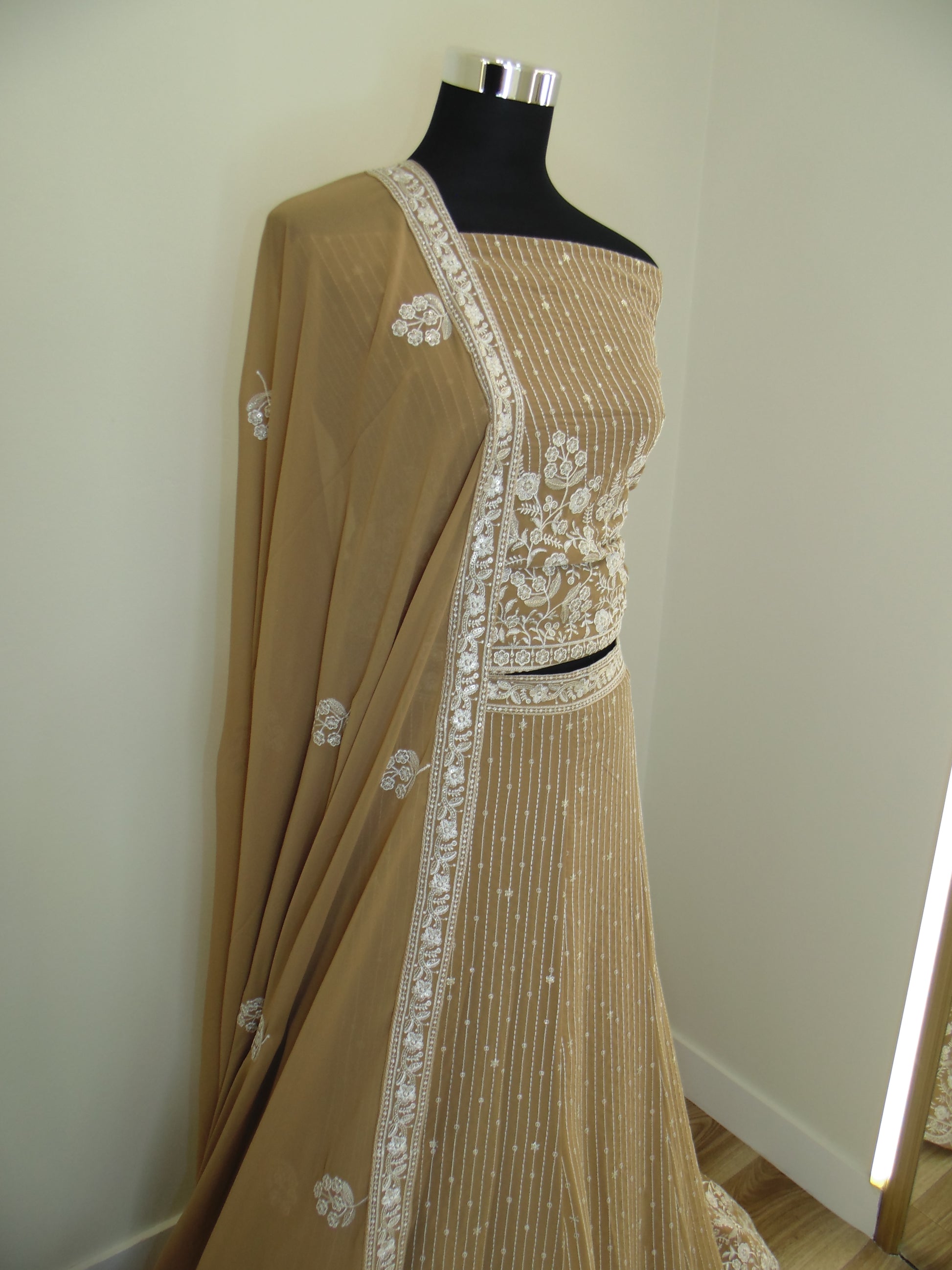 Brown Indian Lehenga with white floral patterns on a mannequin against a neutral background