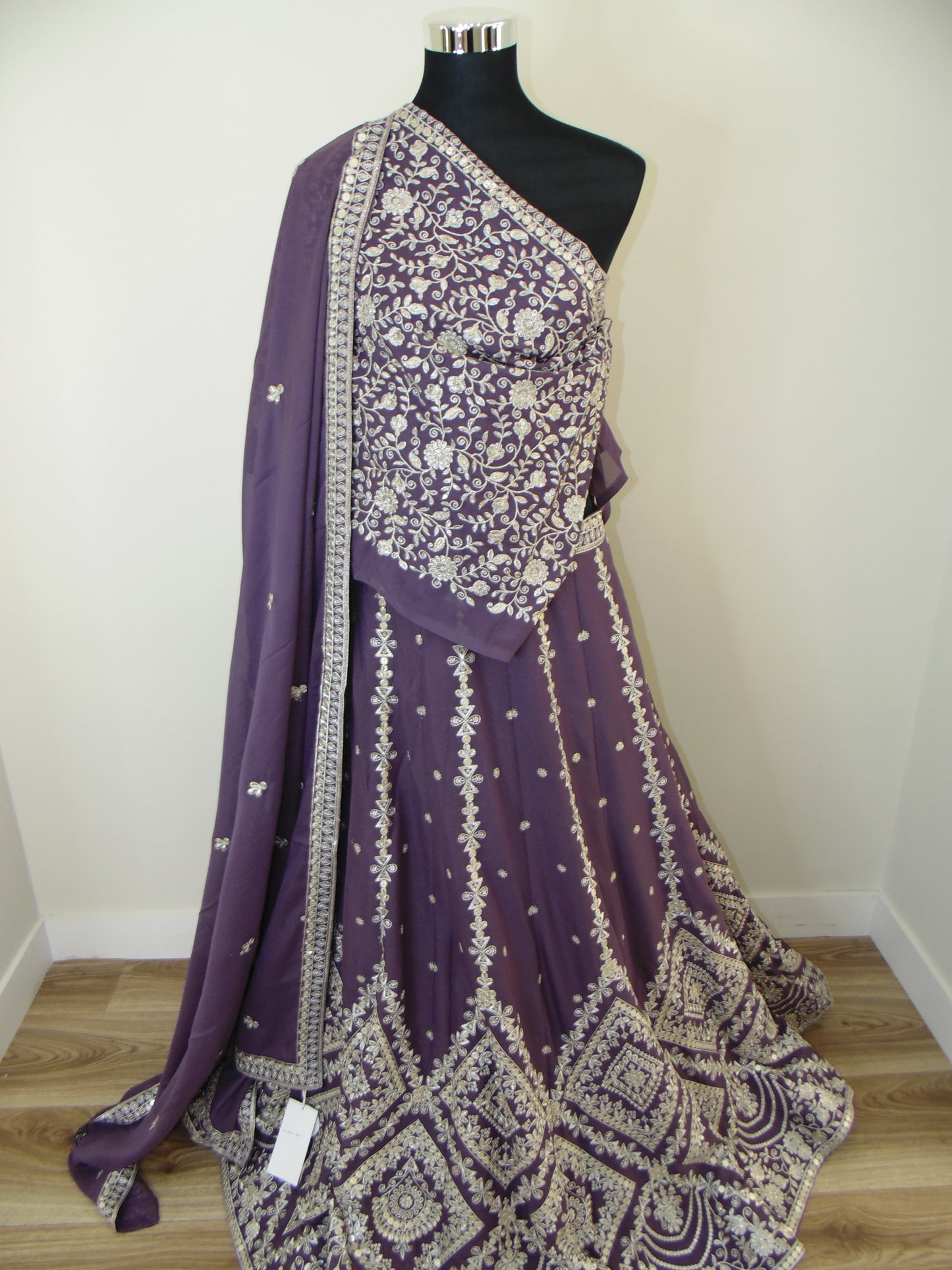 Purple embroidered Indian Lehenga on a mannequin against a white wall.