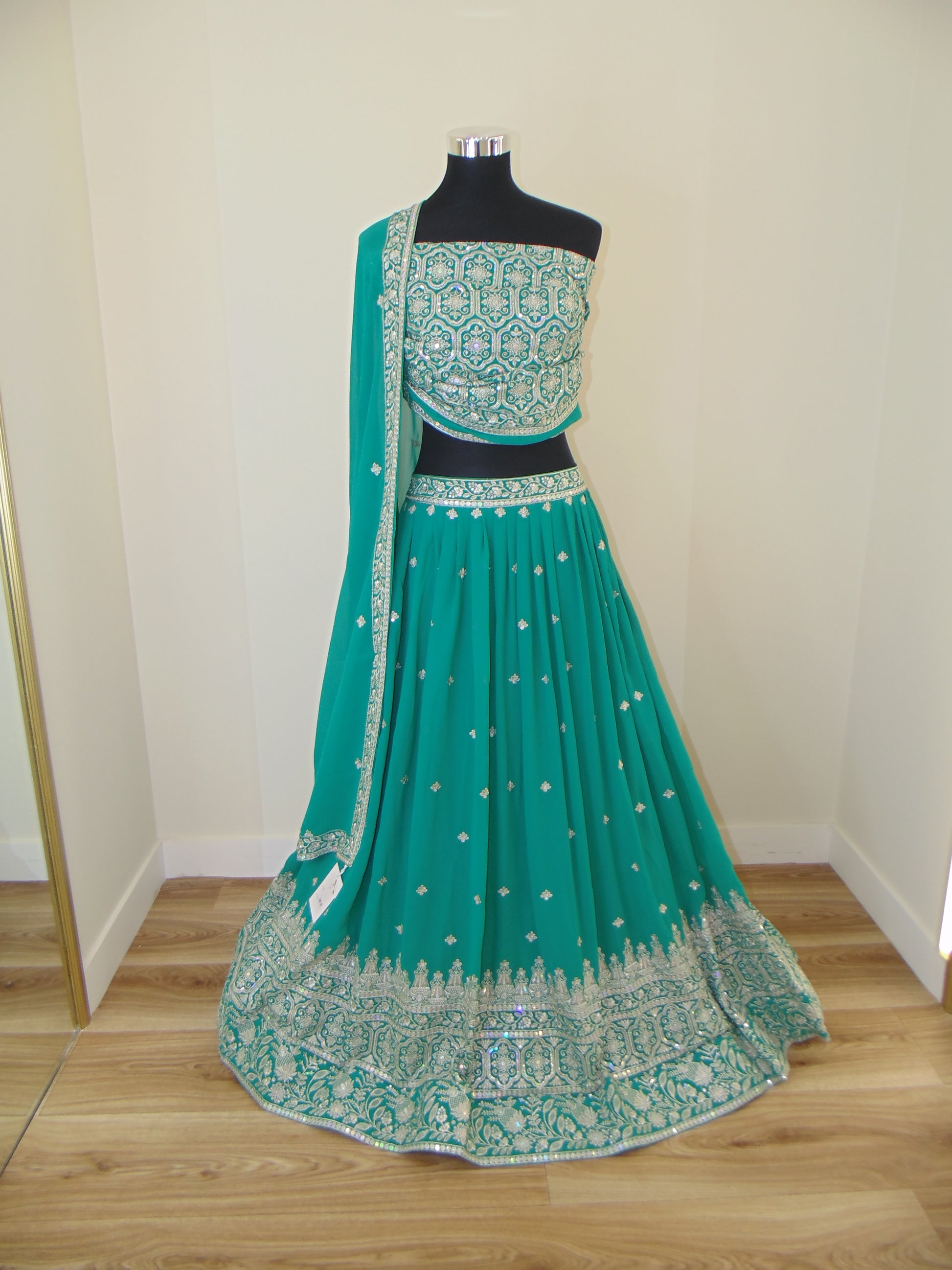 Green embroidered Lehenga with a blouse on a white surface