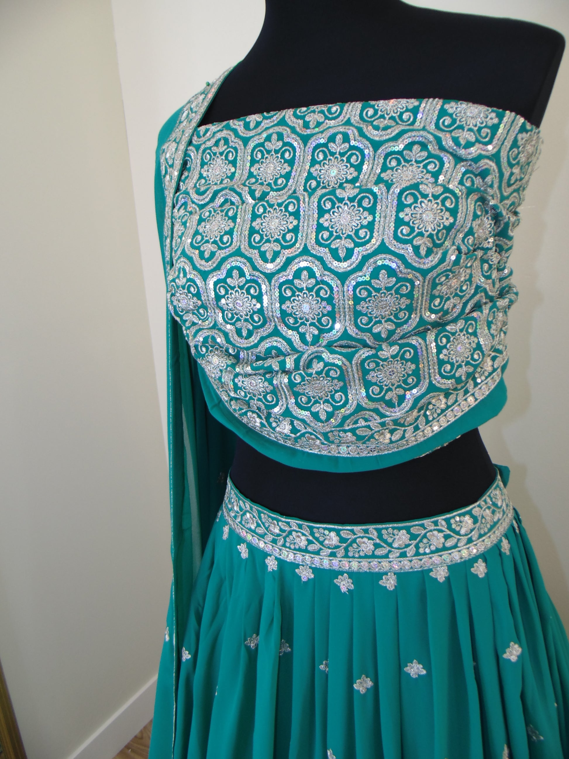 Teal Indian Lehenga with intricate white patterns on a white background