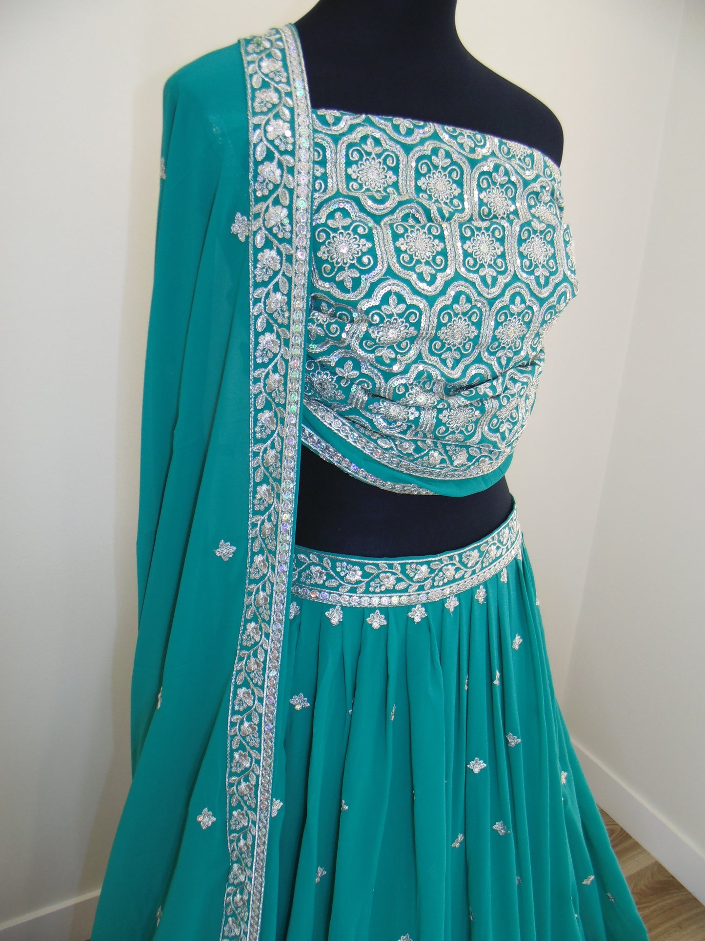 Teal Green Lehenga with white zari embroidery on a white background
