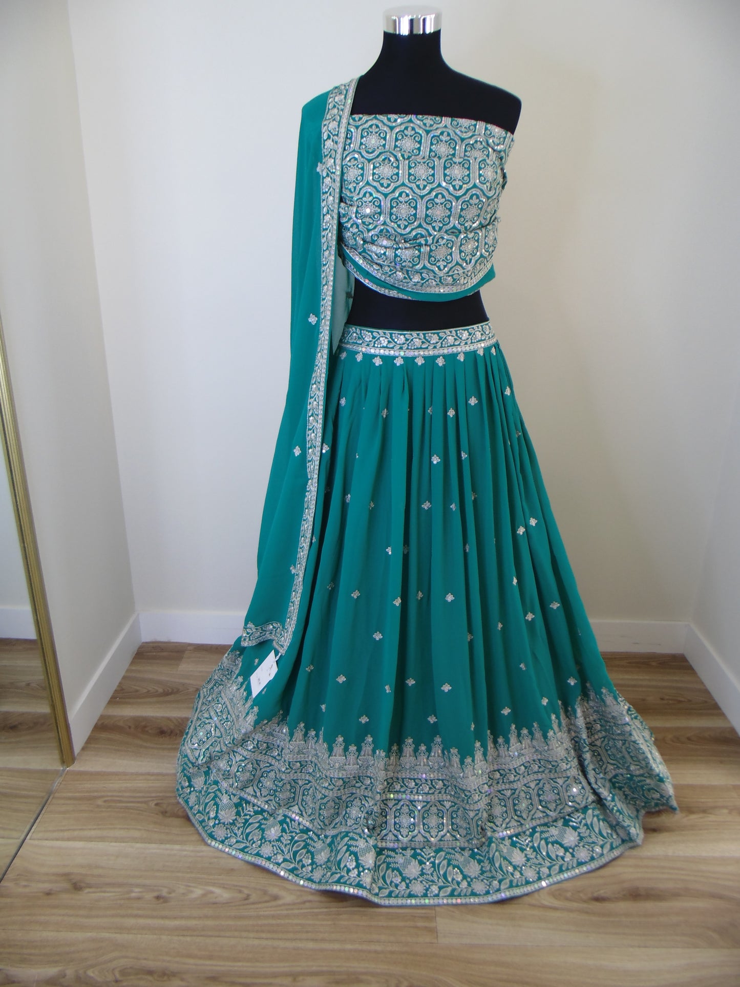 Teal saree with silver border on a white surface