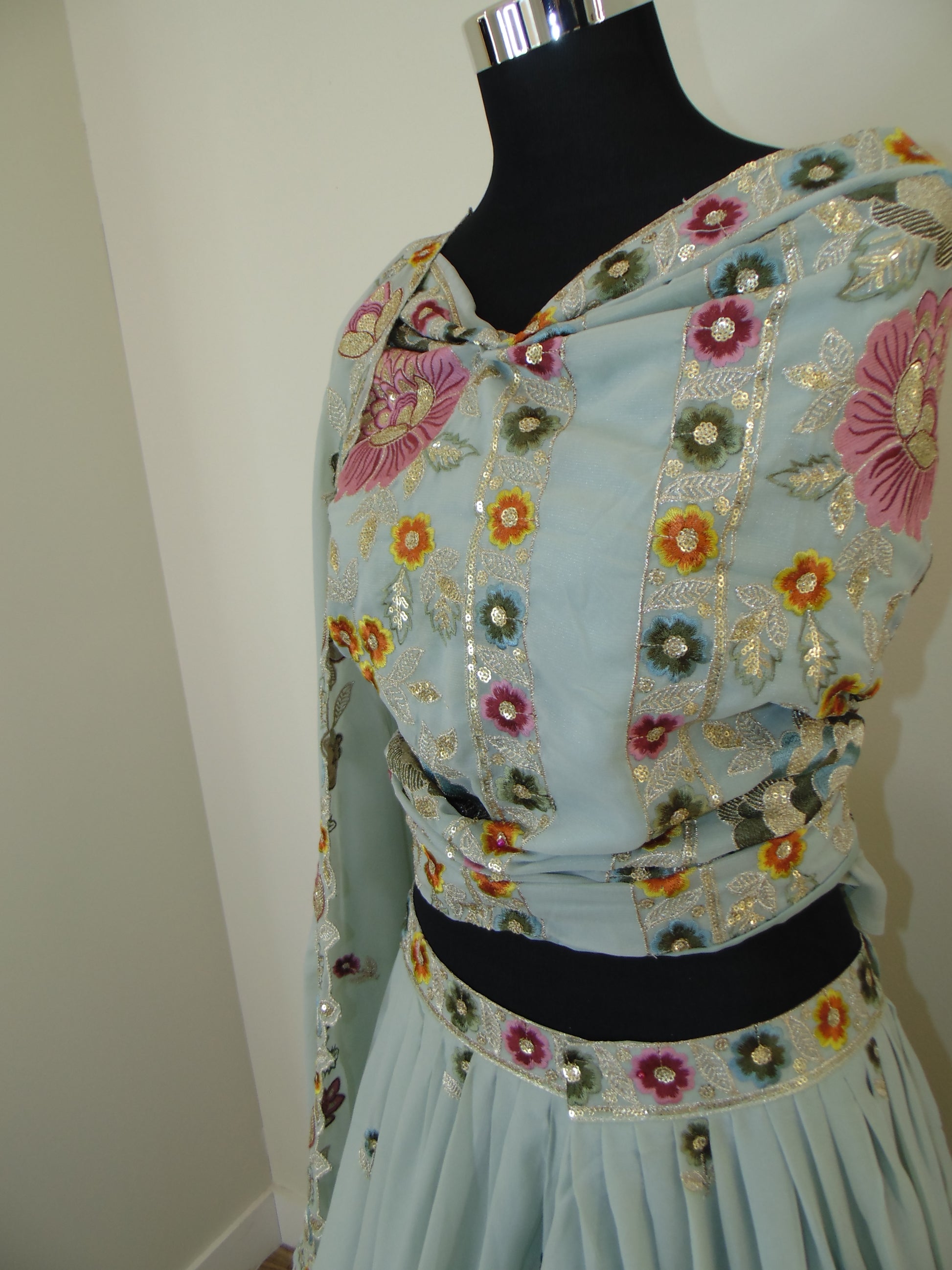 Light blue Indian Lehenga with floral embroidery on a mannequin against a white wall.