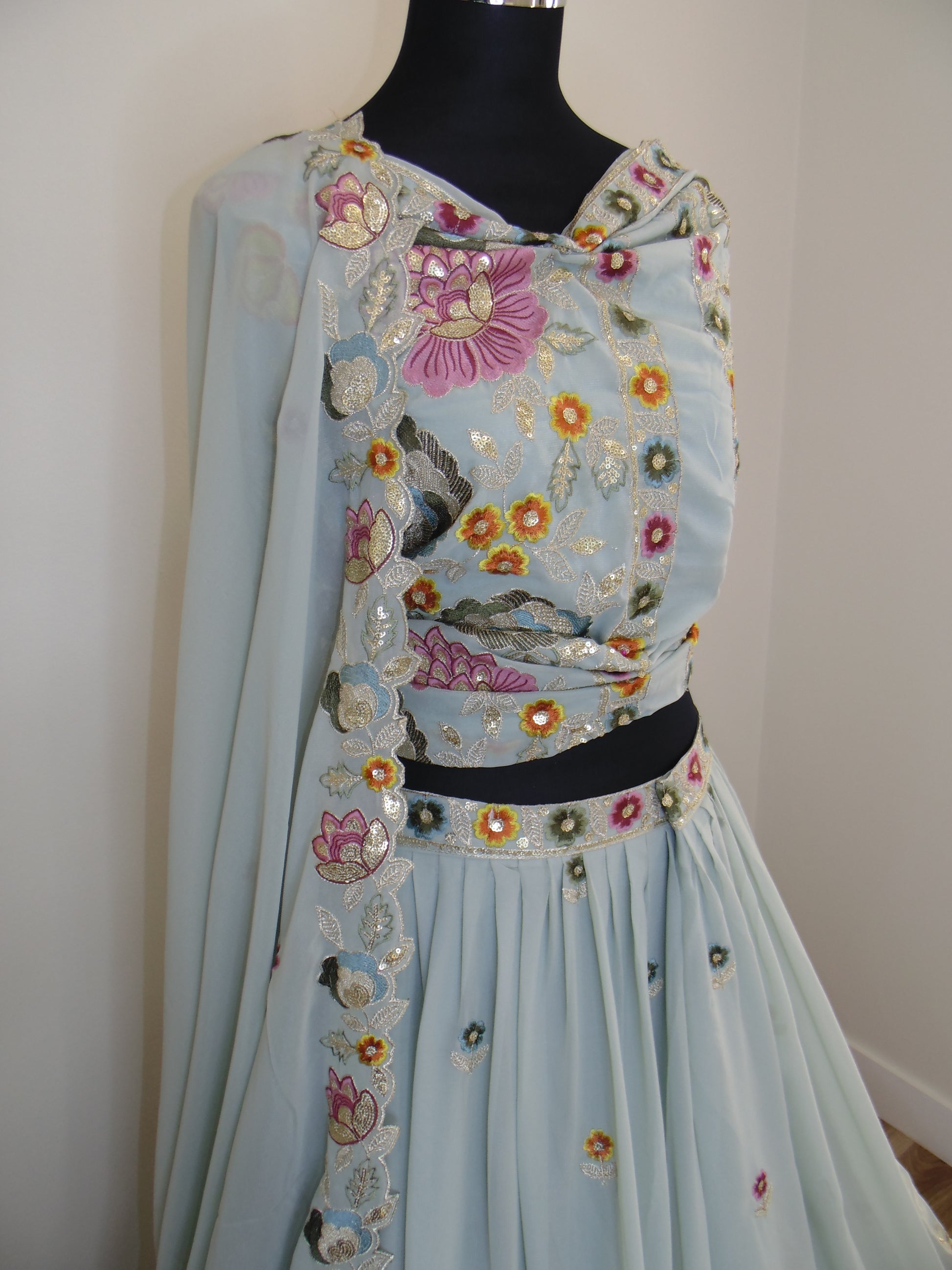 Light blue dress with floral embroidery on a mannequin against a white background