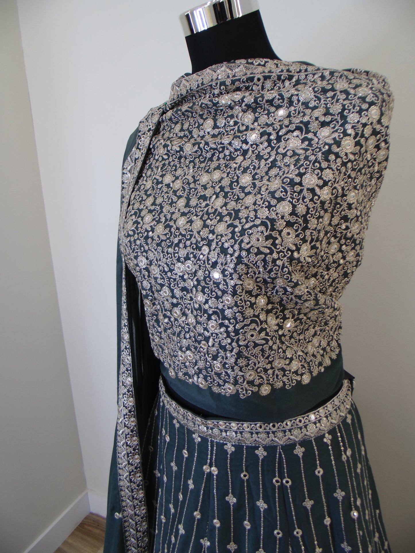 Mannequin wearing a floral Lehenga with silver embellishments on a plain background