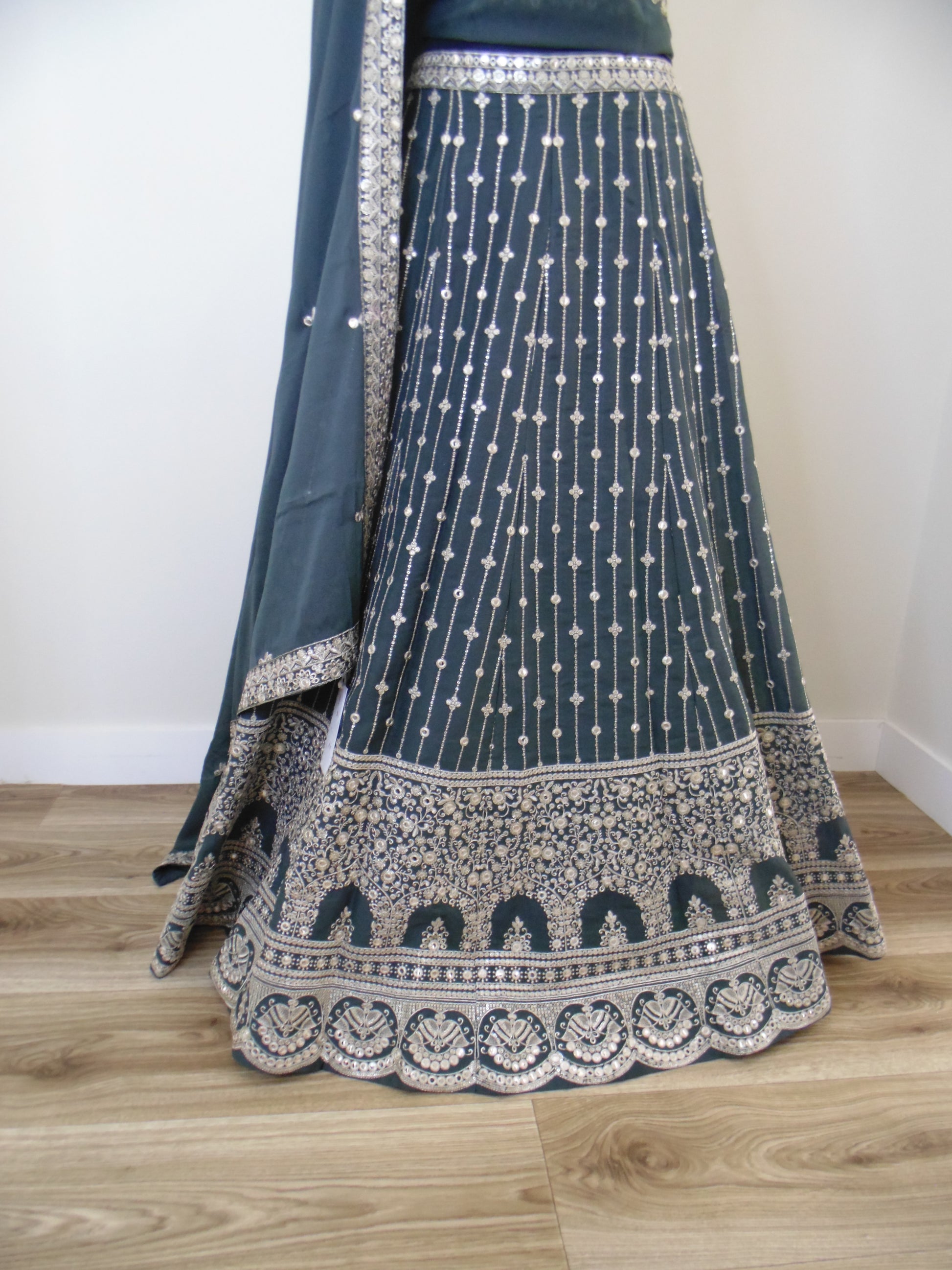 Blue Lehenga with intricate patterns on a wooden floor