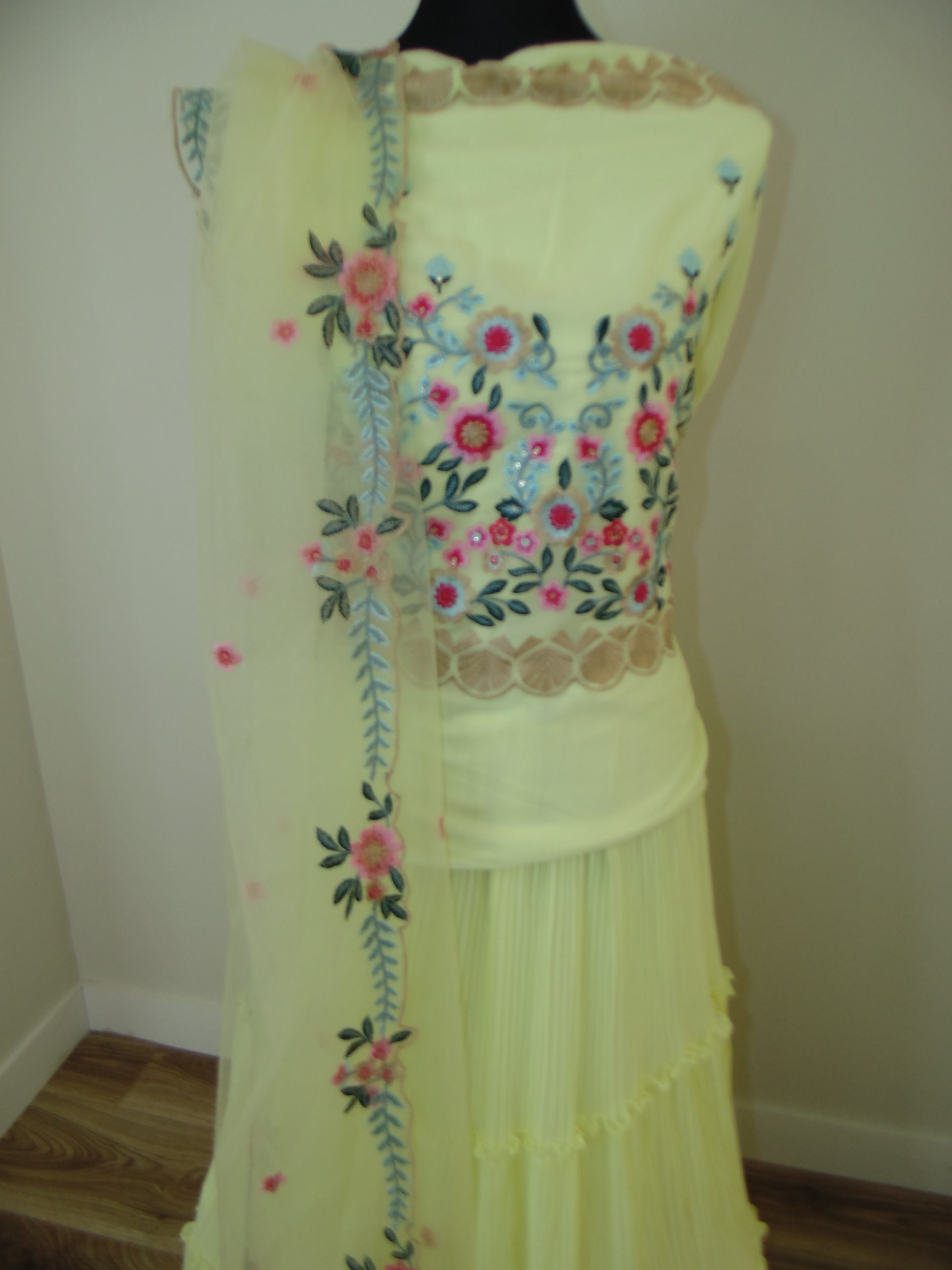 Embroidered yellow dress on a mannequin with floral patterns.