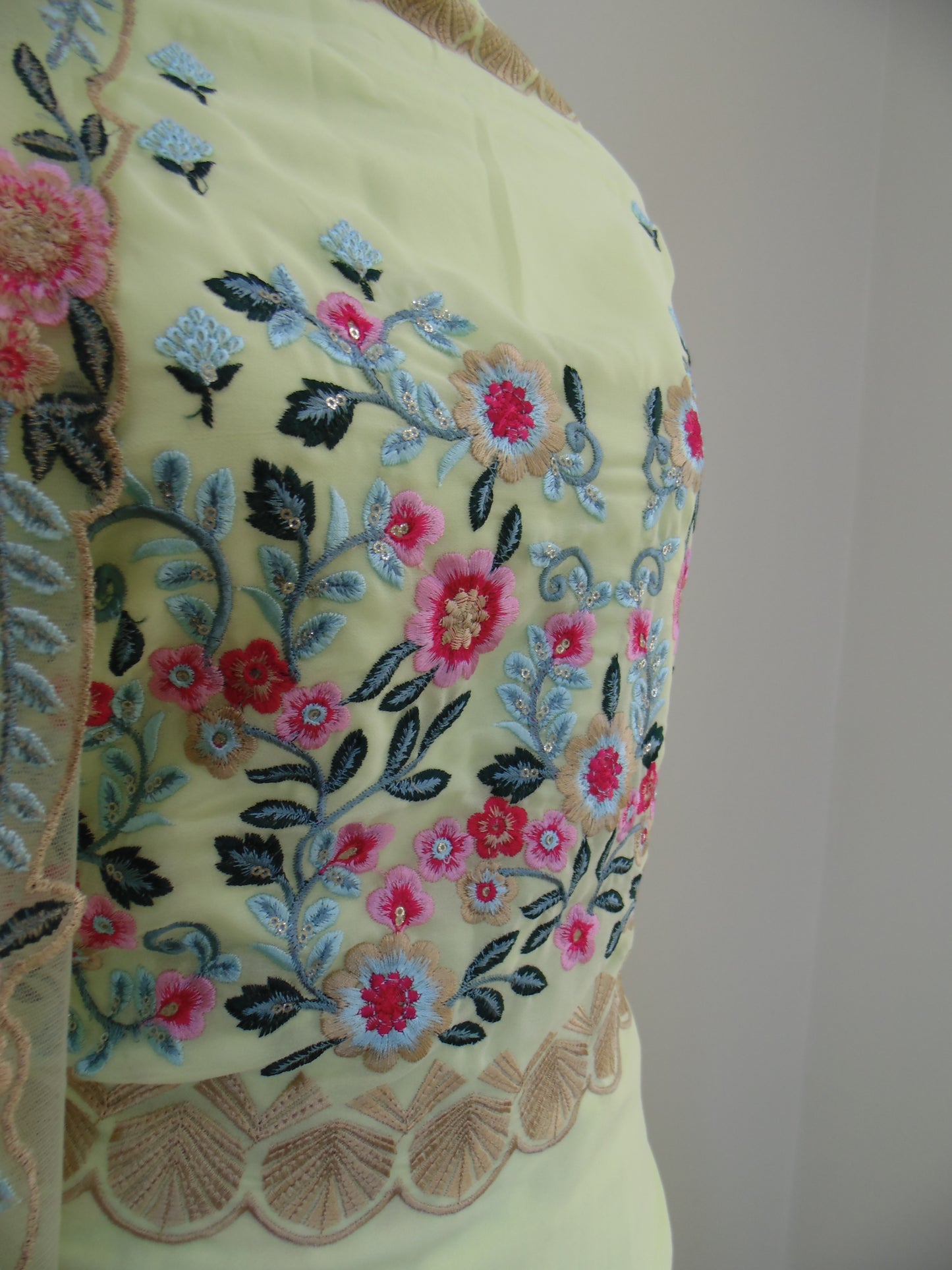 Embroidered floral design on a light yellow fabric with a white background