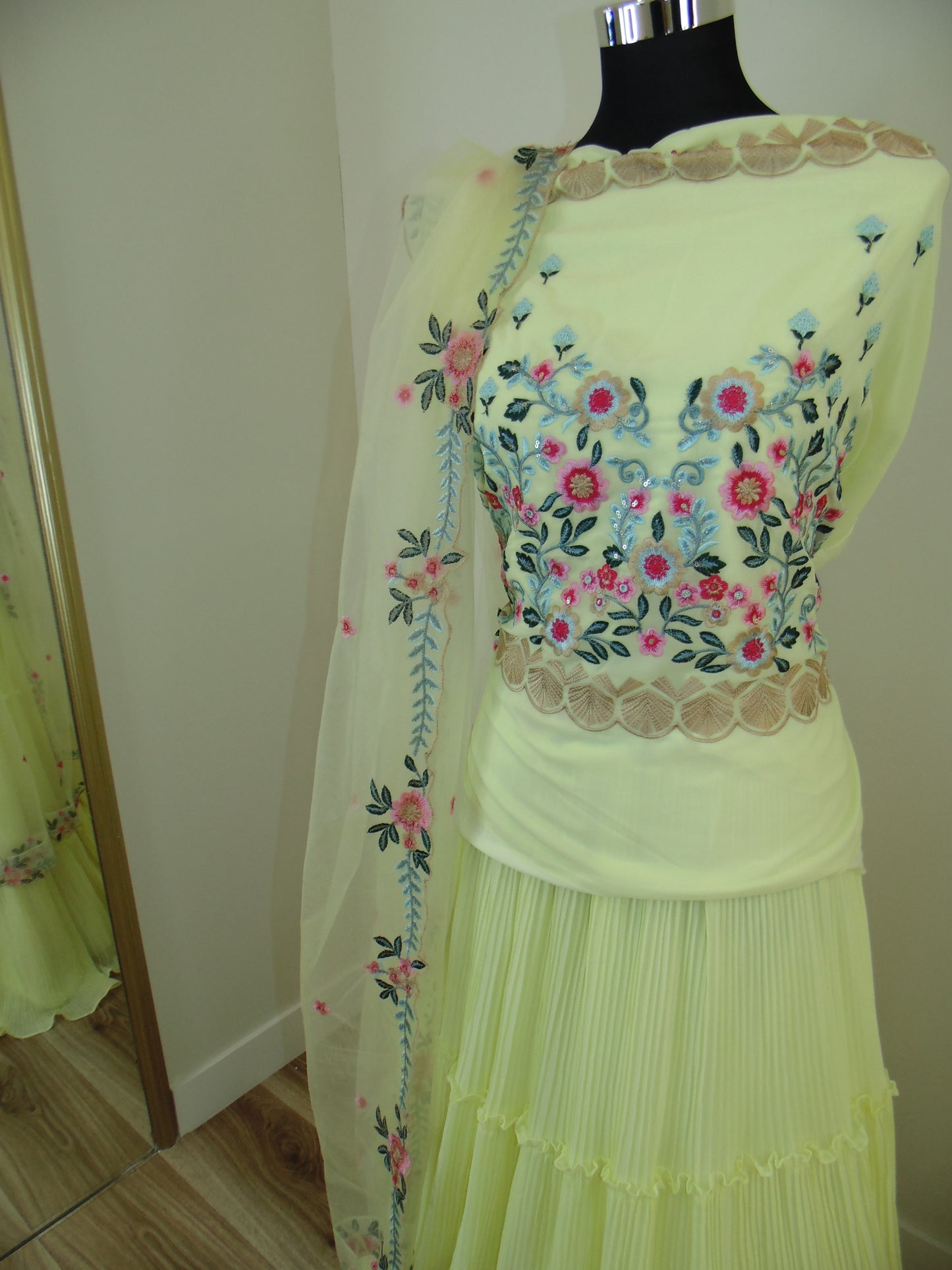Light green dress with floral embroidery on a mannequin against a neutral background