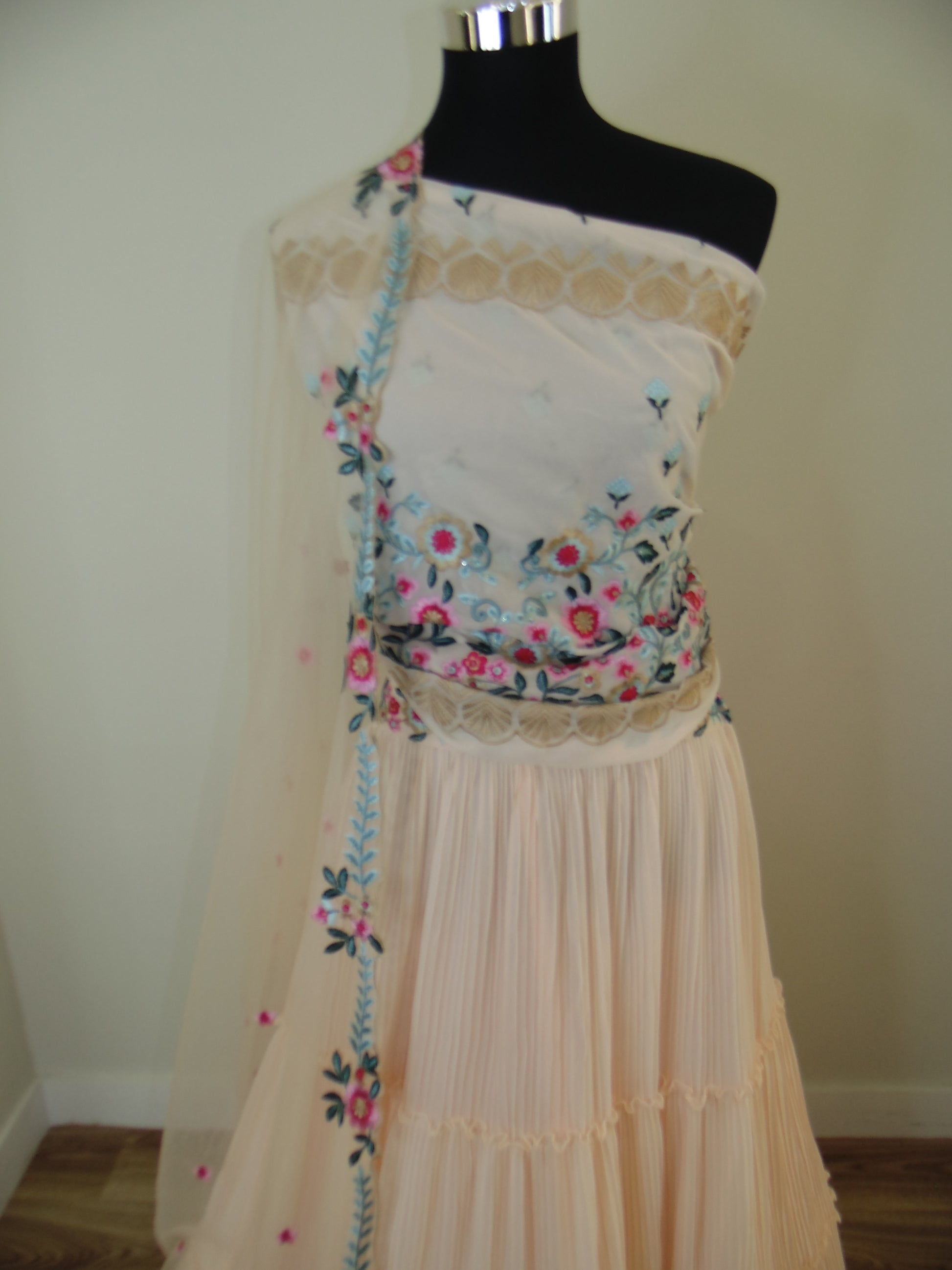 Mannequin wearing a floral pleated skirt on a plain background