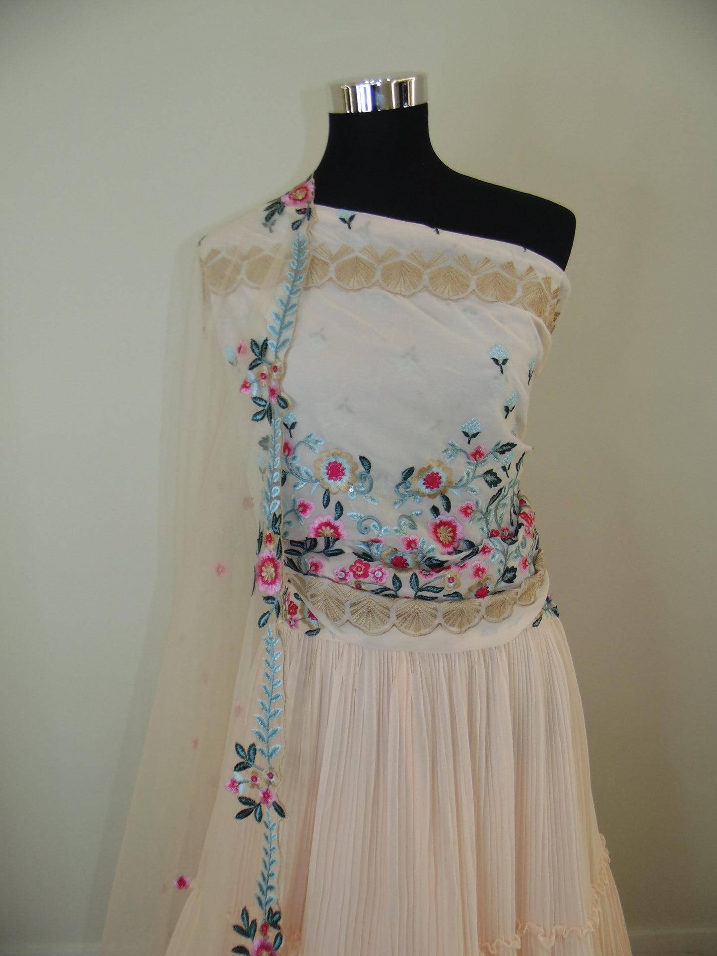 Mannequin wearing a floral dress with pleated skirt on a plain background