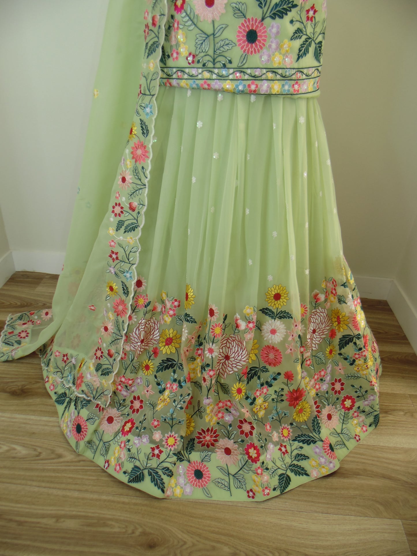 Light green Lehenga with floral embroidery on a wooden surface