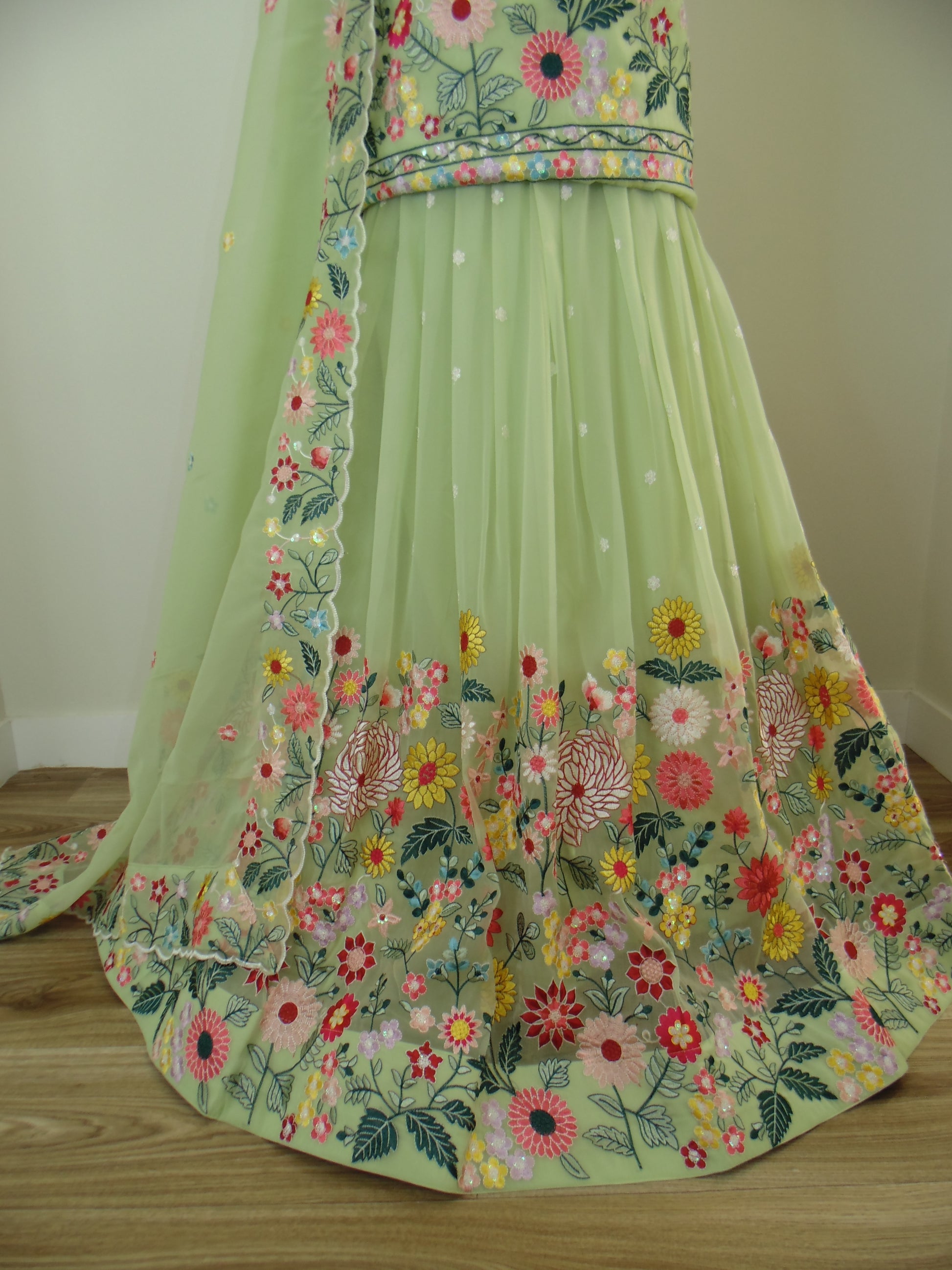Green fabric with floral embroidery on a wooden surface
