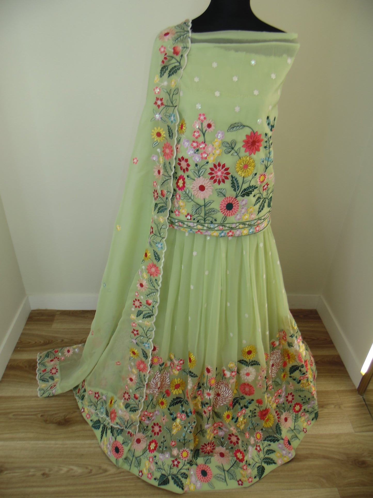 Green dress with floral embroidery on a wooden surface