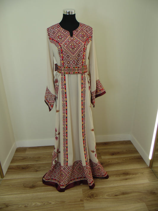 Traditional embroidered Palestinian Thobe on a mannequin against a white wall