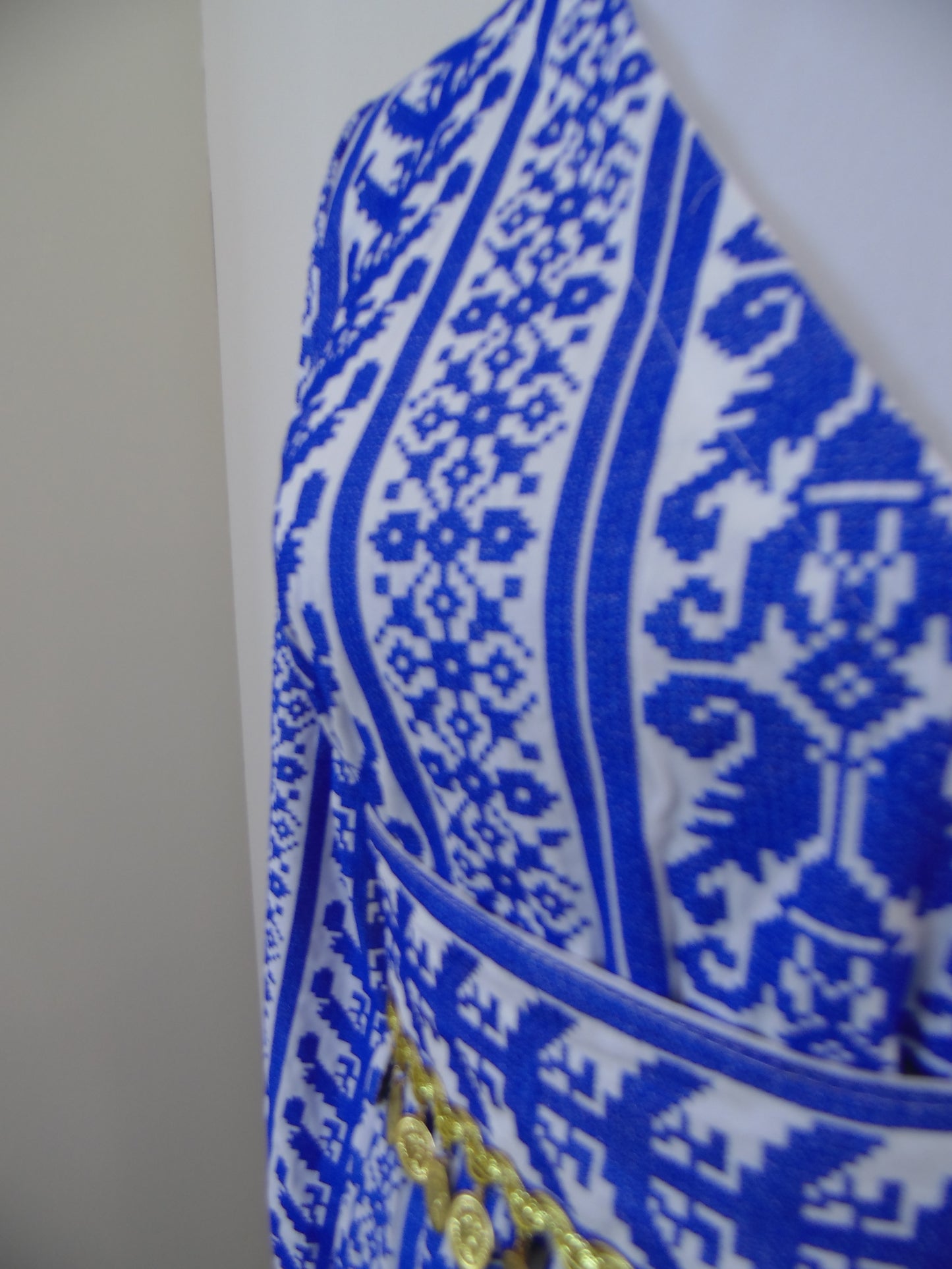 Close-up of a blue and white patterned fabric with gold accents on a plain background