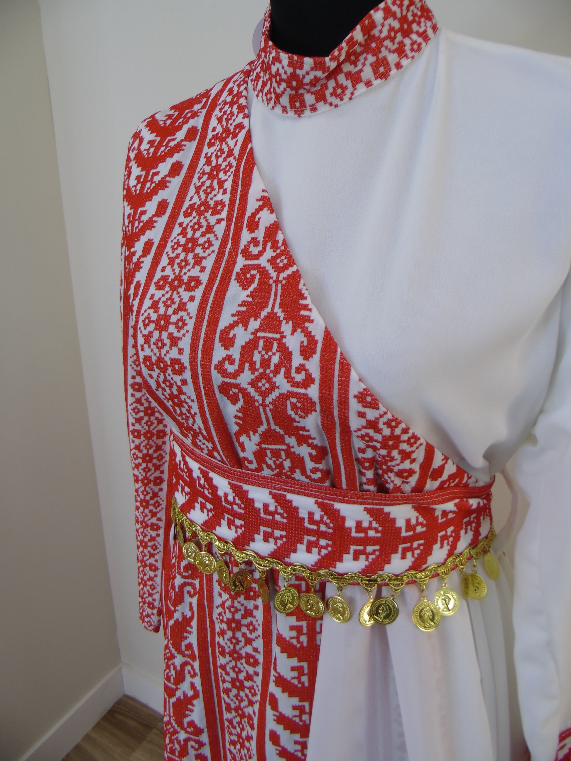 Traditional embroidered garment with red and white patterns on a white background