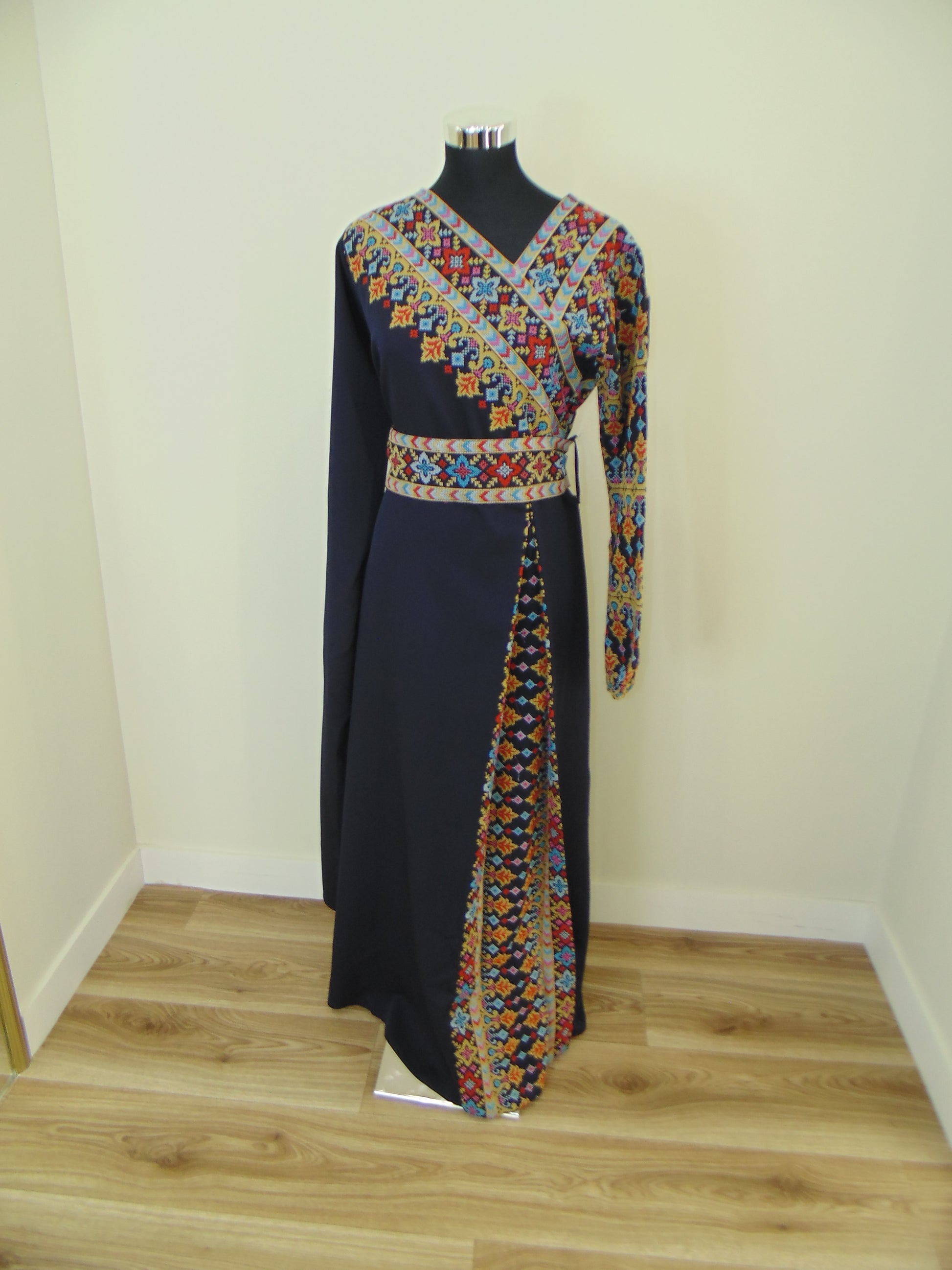 Black garment with colorful floral embroidery on a white surface.