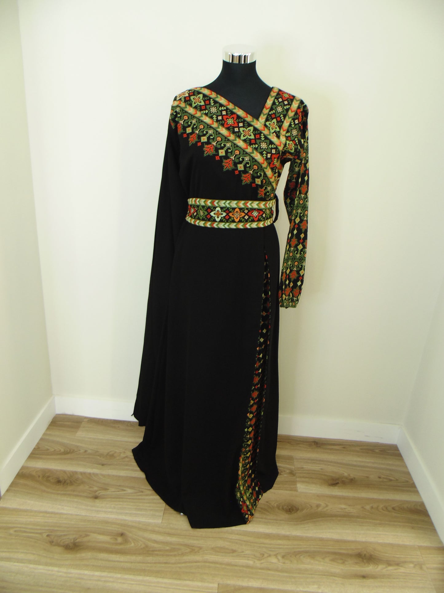 Black dress with colorful embroidery on a white surface