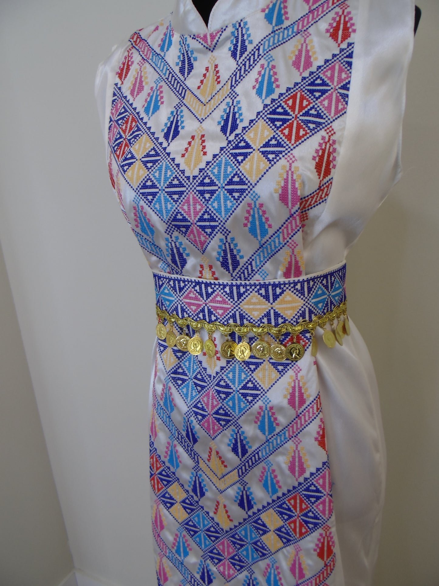 Colorful embroidered palestinian thobe with geometric patterns on a white background