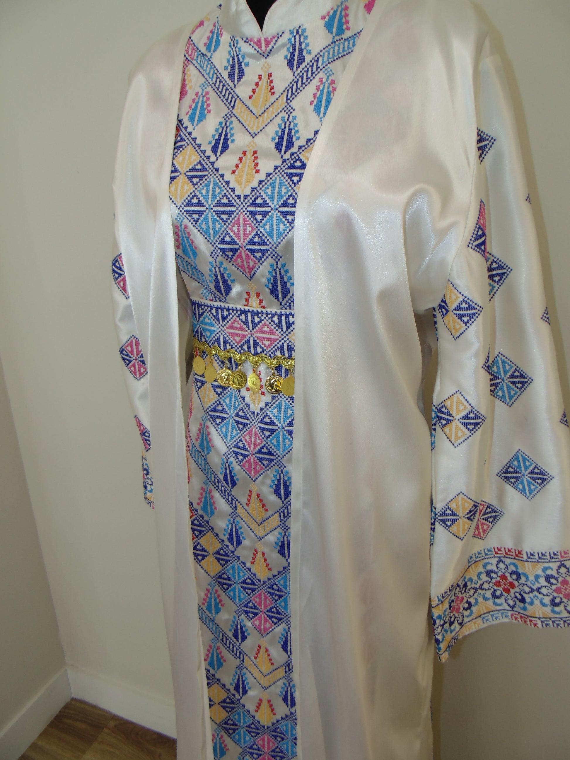 Traditional embroidered dress with geometric patterns on a plain background