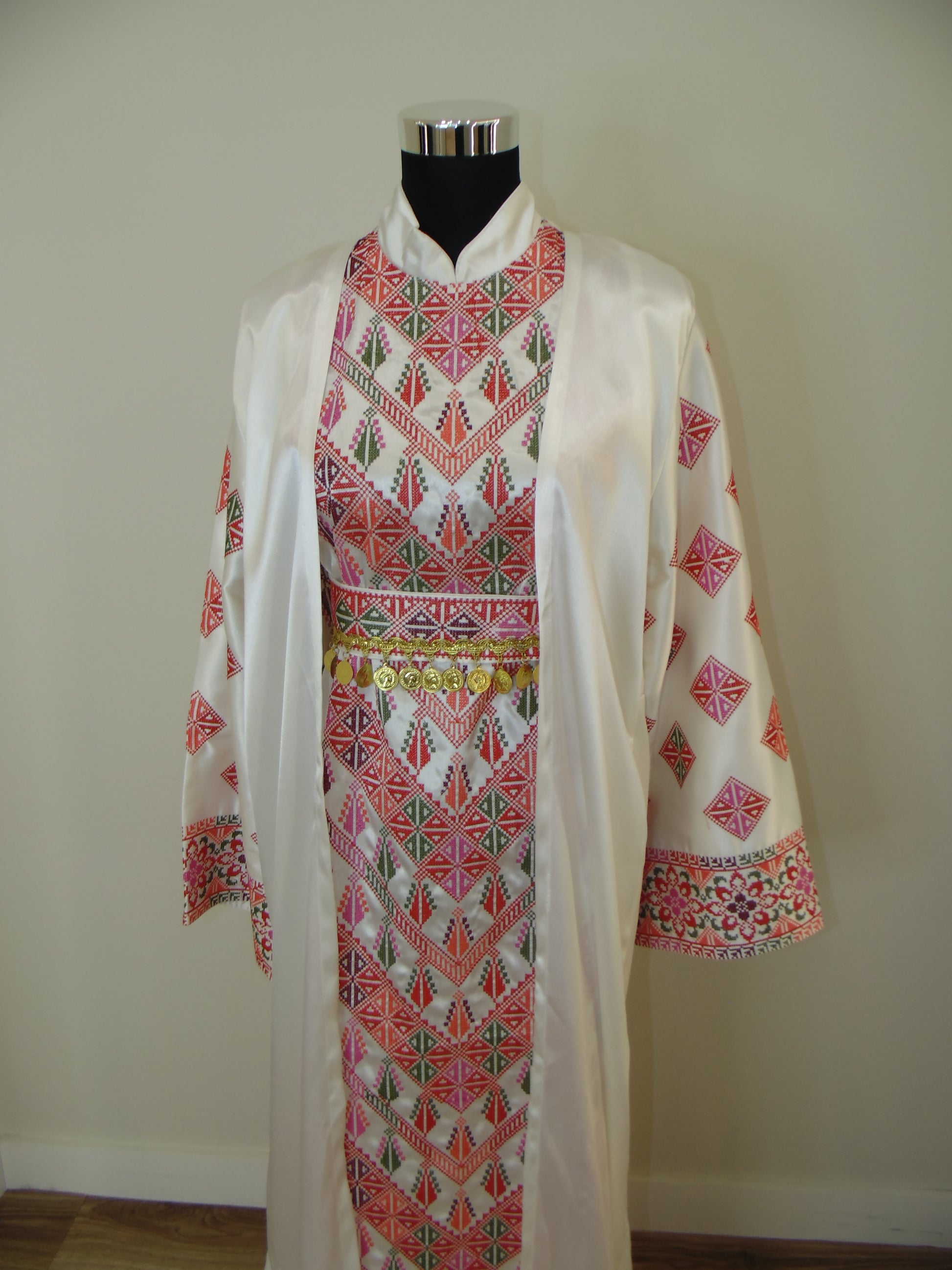 Traditional embroidered palestinian thobe on a hanger against a plain background