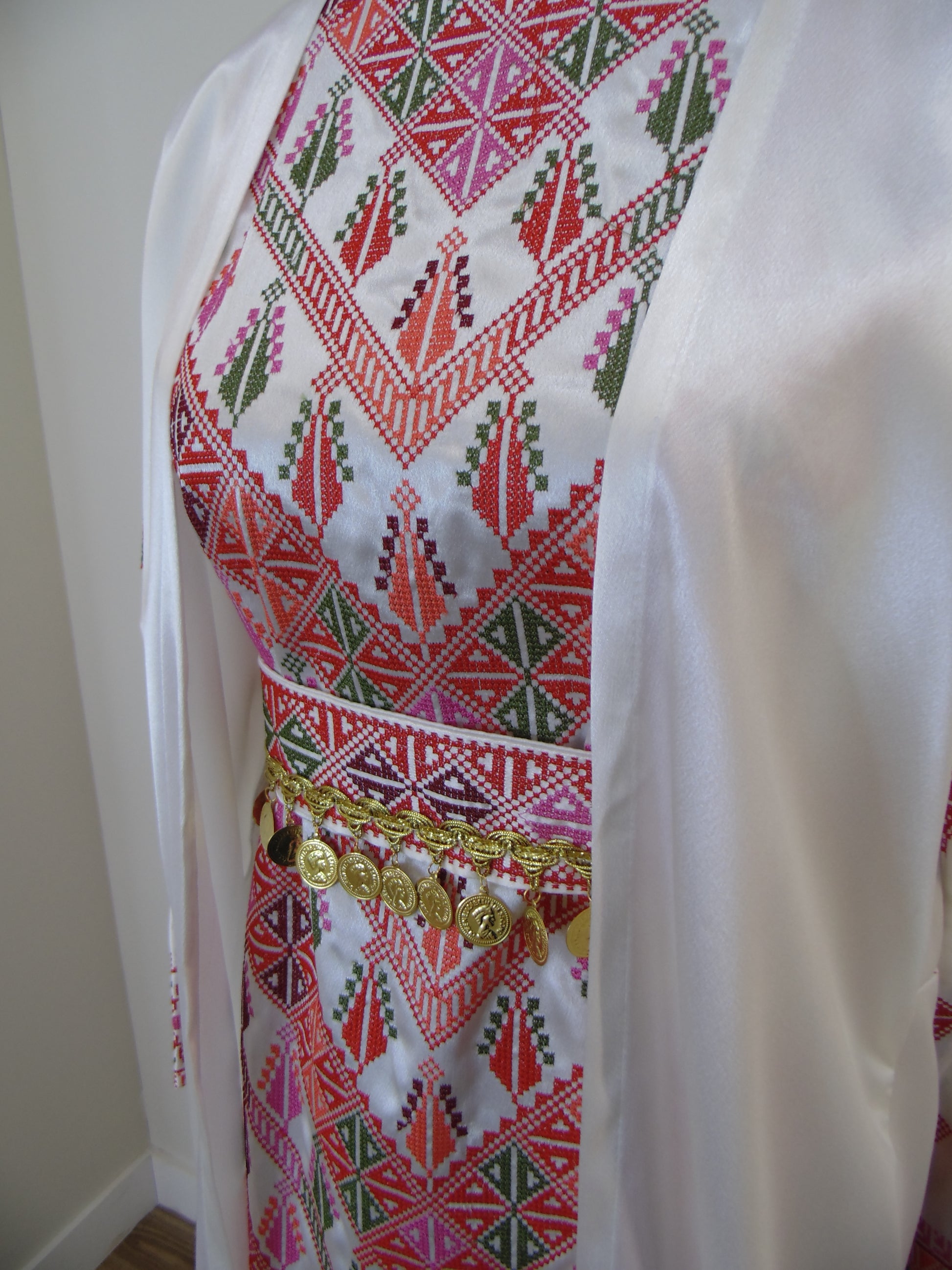 Embroidered fabric with geometric patterns and gold accents on a white background