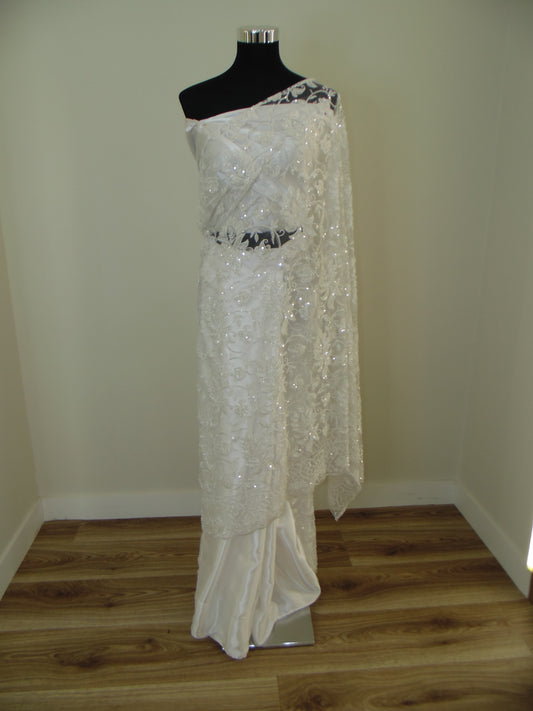 White beaded Indian Saree on a mannequin against a plain wall.