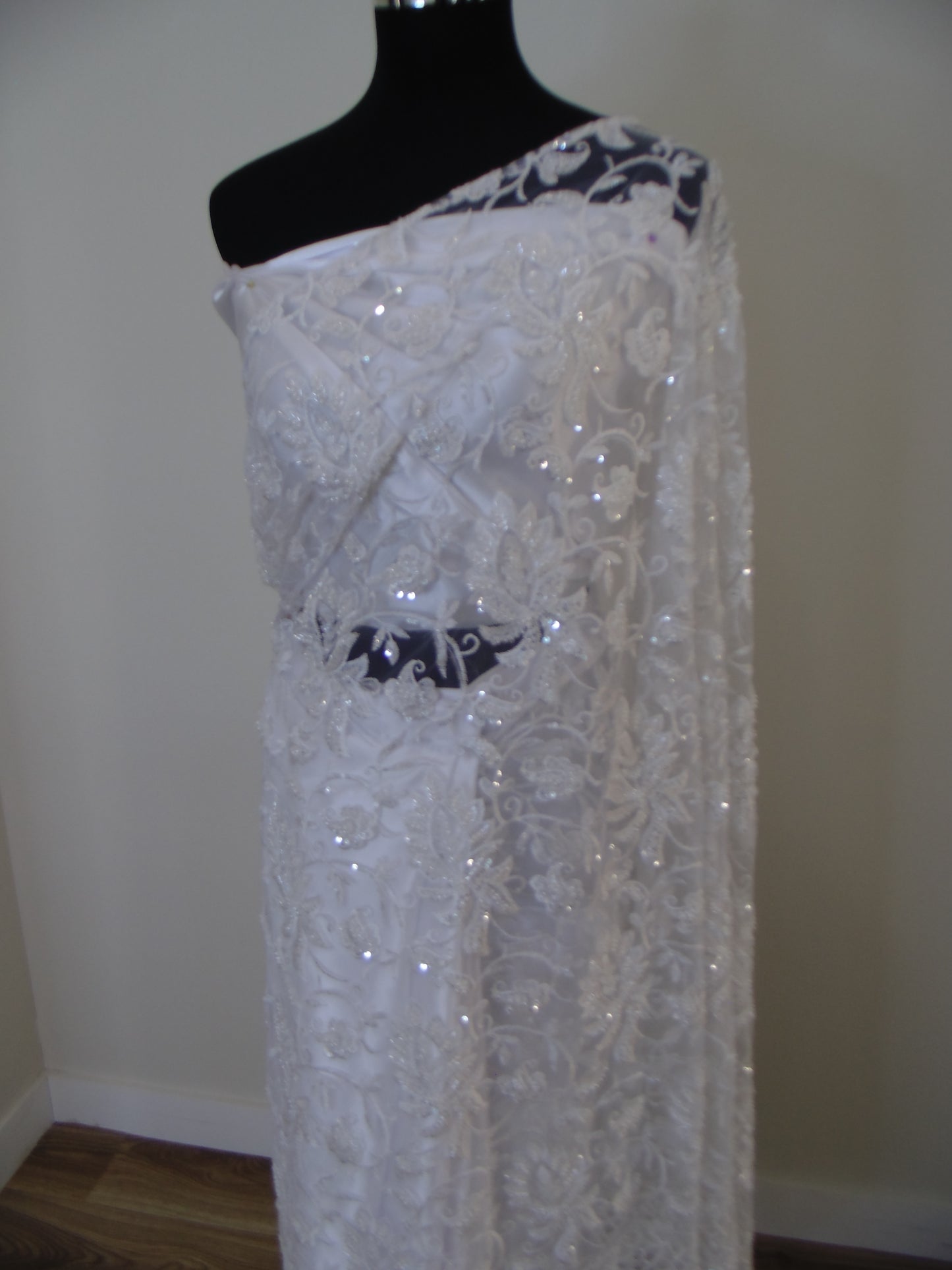 White lace Saree on a mannequin with a plain background