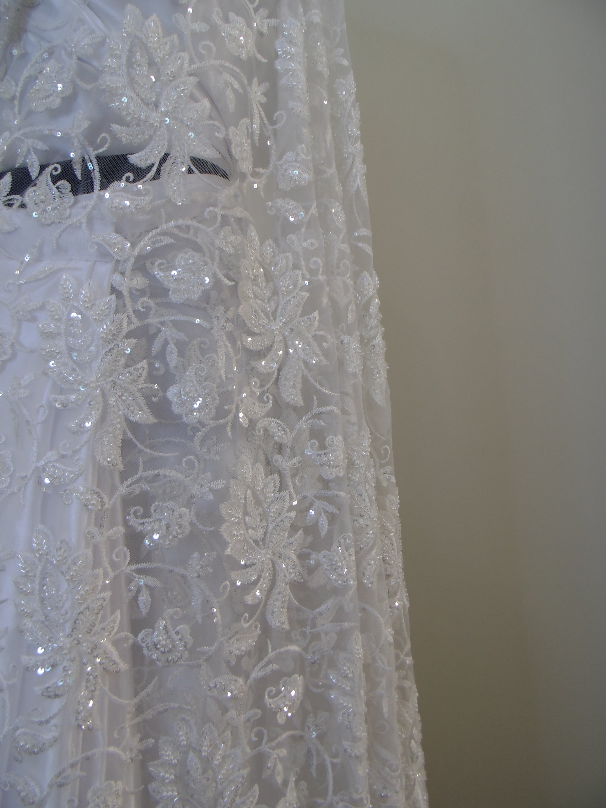 Close-up of intricate lace fabric with floral patterns on a plain background