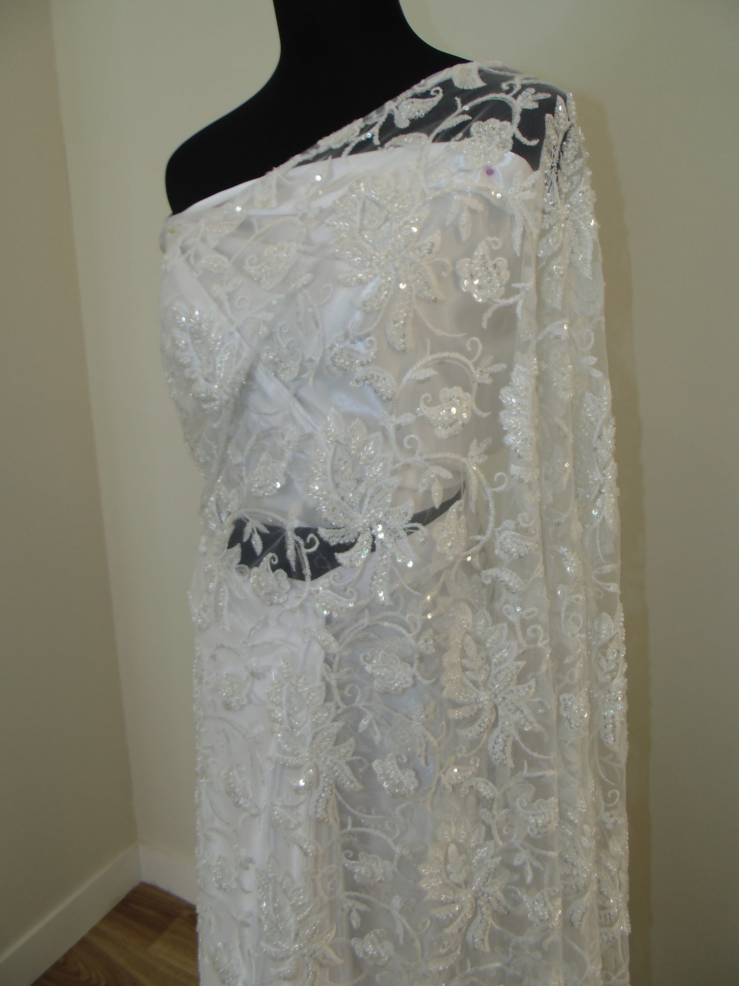 White lace Indian Saree on a mannequin against a neutral background