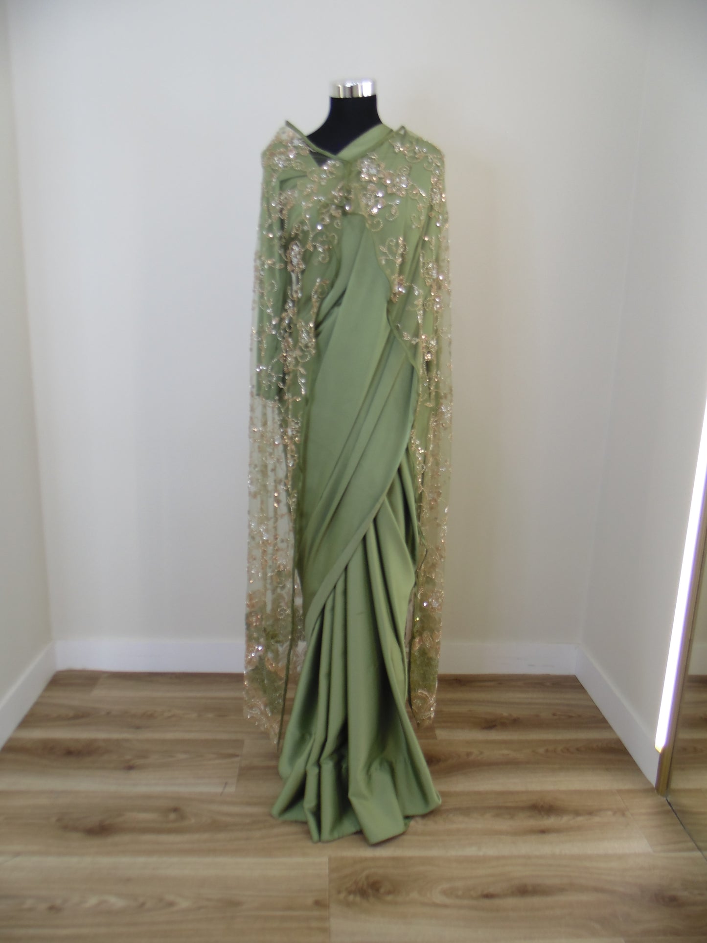 Green Saree with sequins works cardigan on a mannequin against a white wall.