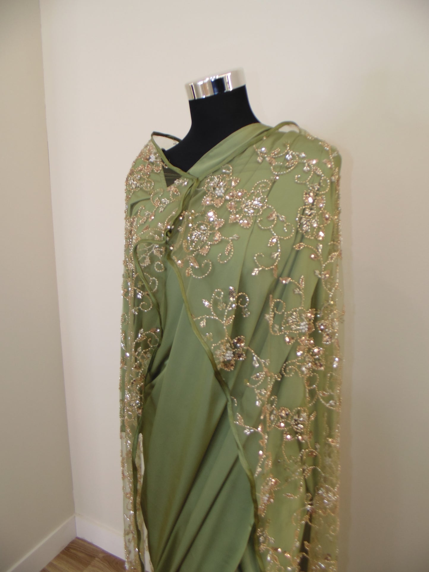 Green evening gown with beaded details on a white surface