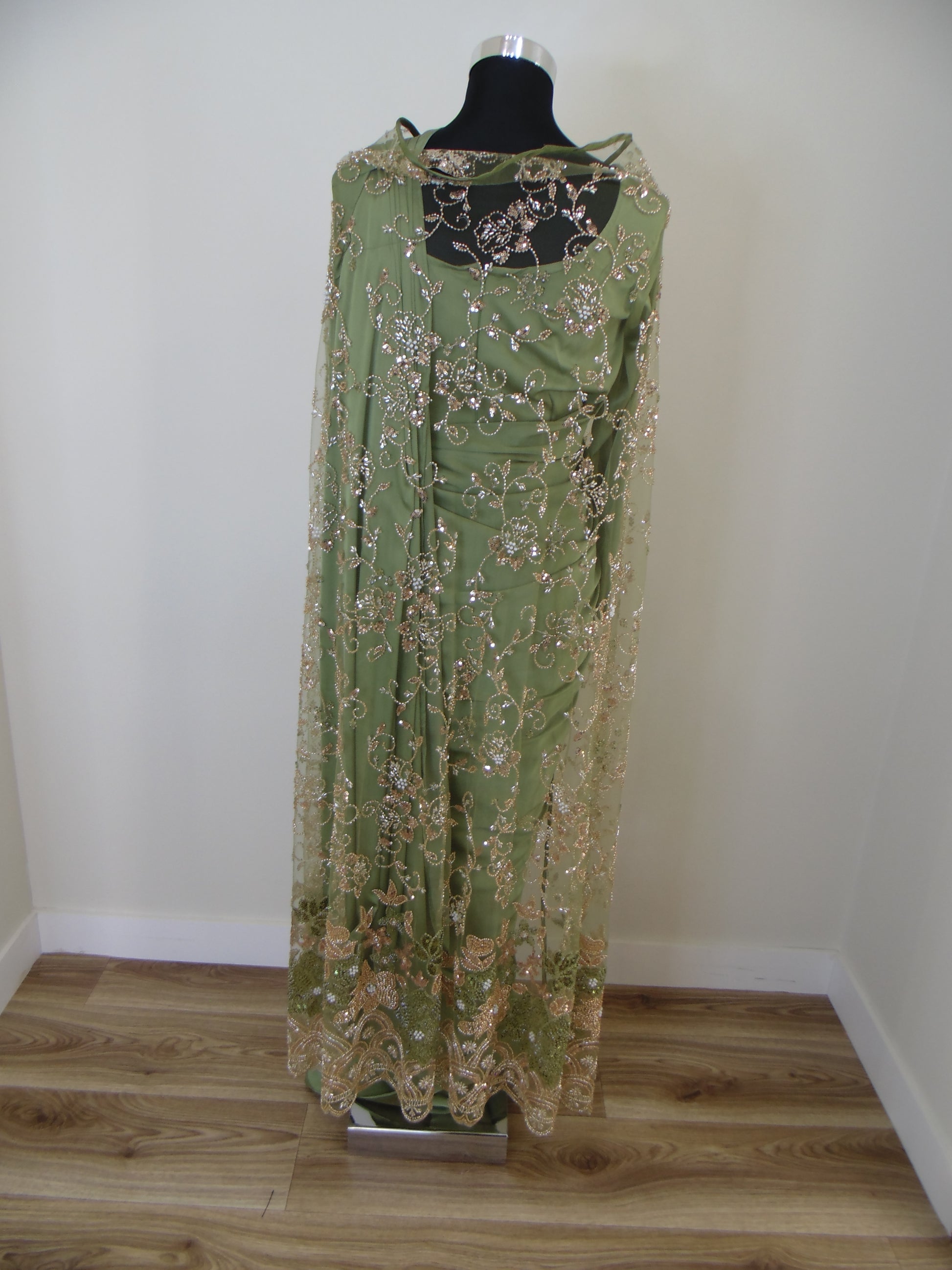 Green embroidered saree with cardigan on a mannequin against a white wall.