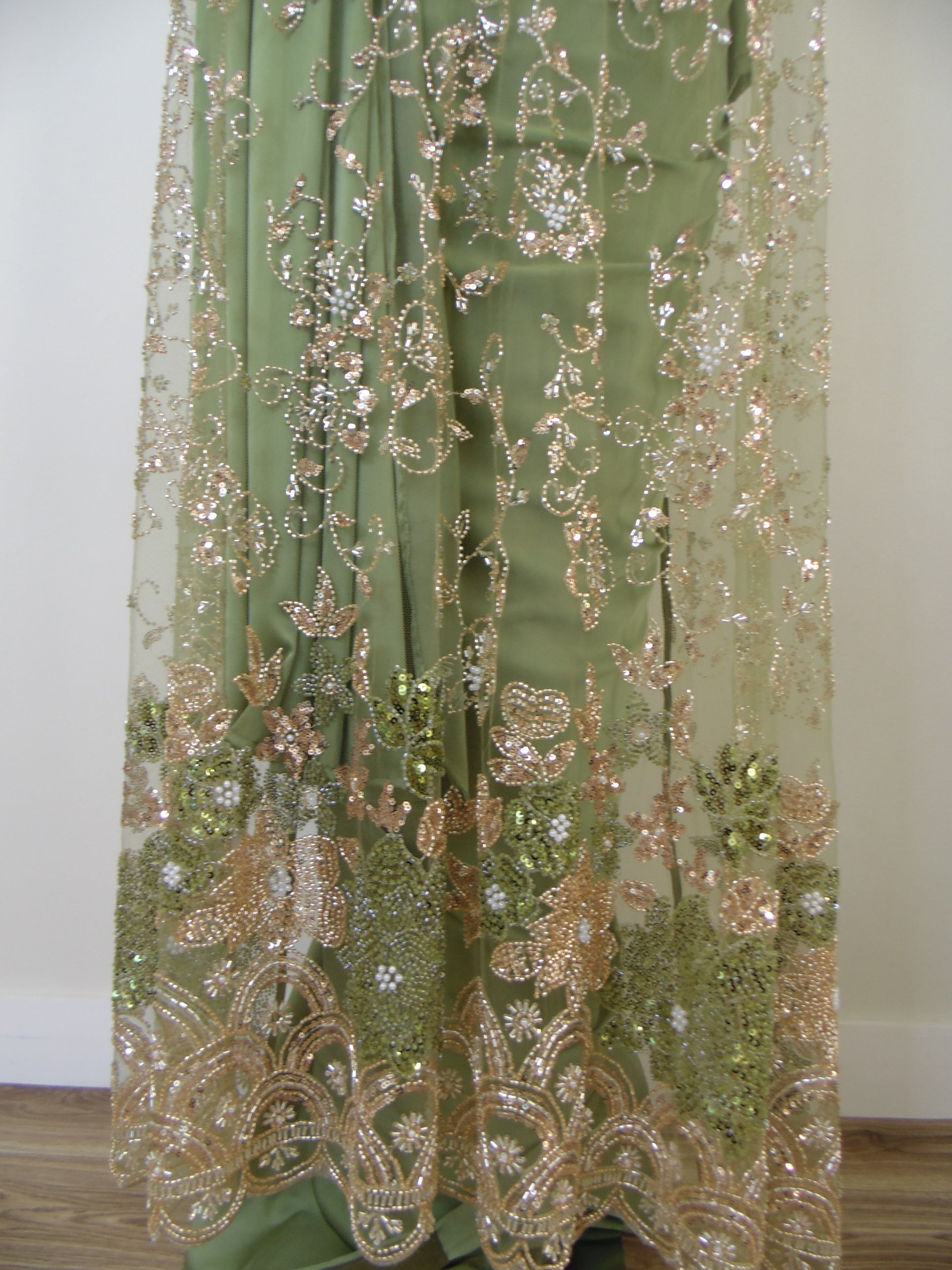 Green fabric with gold embroidery and sequins on a white background