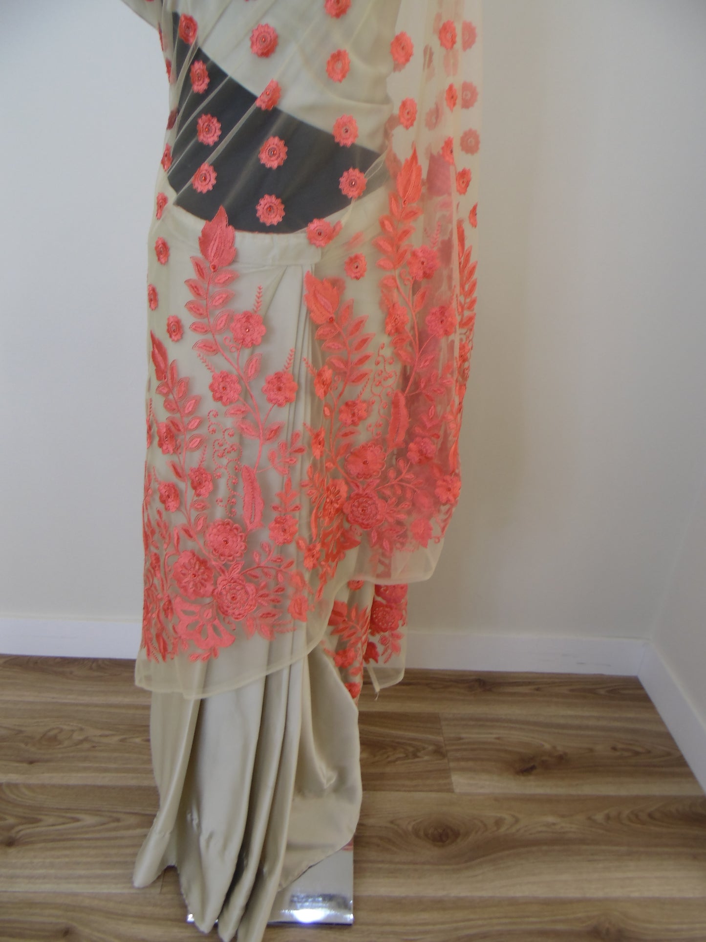 Pre-stitched Saree with orange floral embroidery draped over a wooden surface.