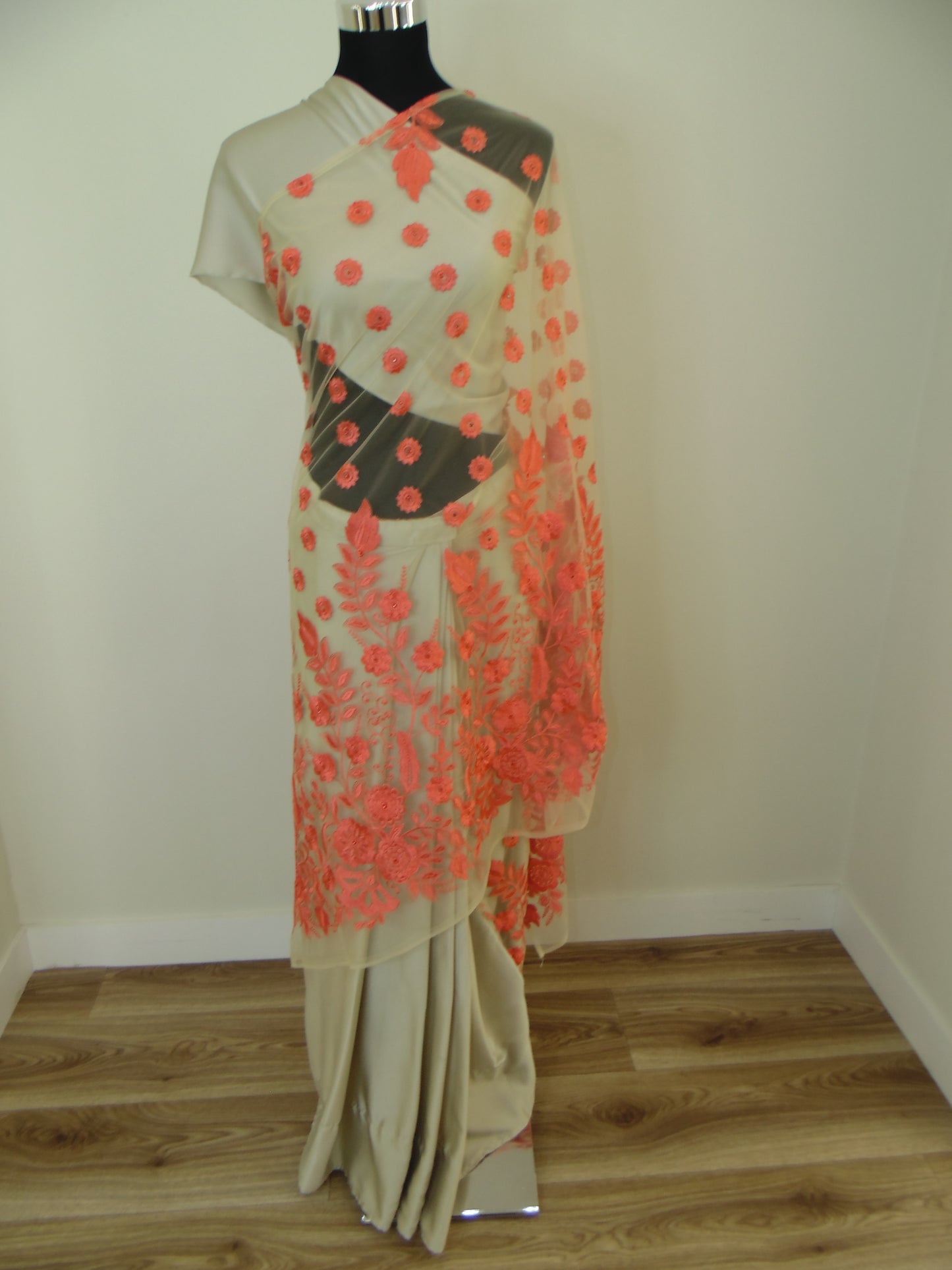 Mannequin wearing a floral ready to wear saree with orange embroidered flowers against a neutral background.