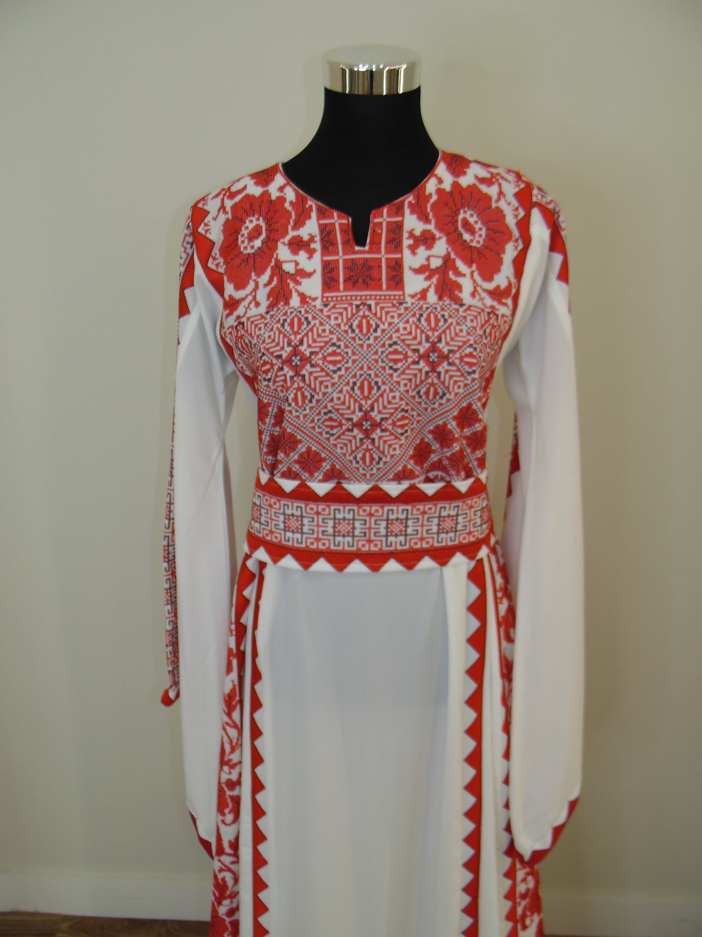 Traditional red and white embroidered dress on a mannequin against a plain background