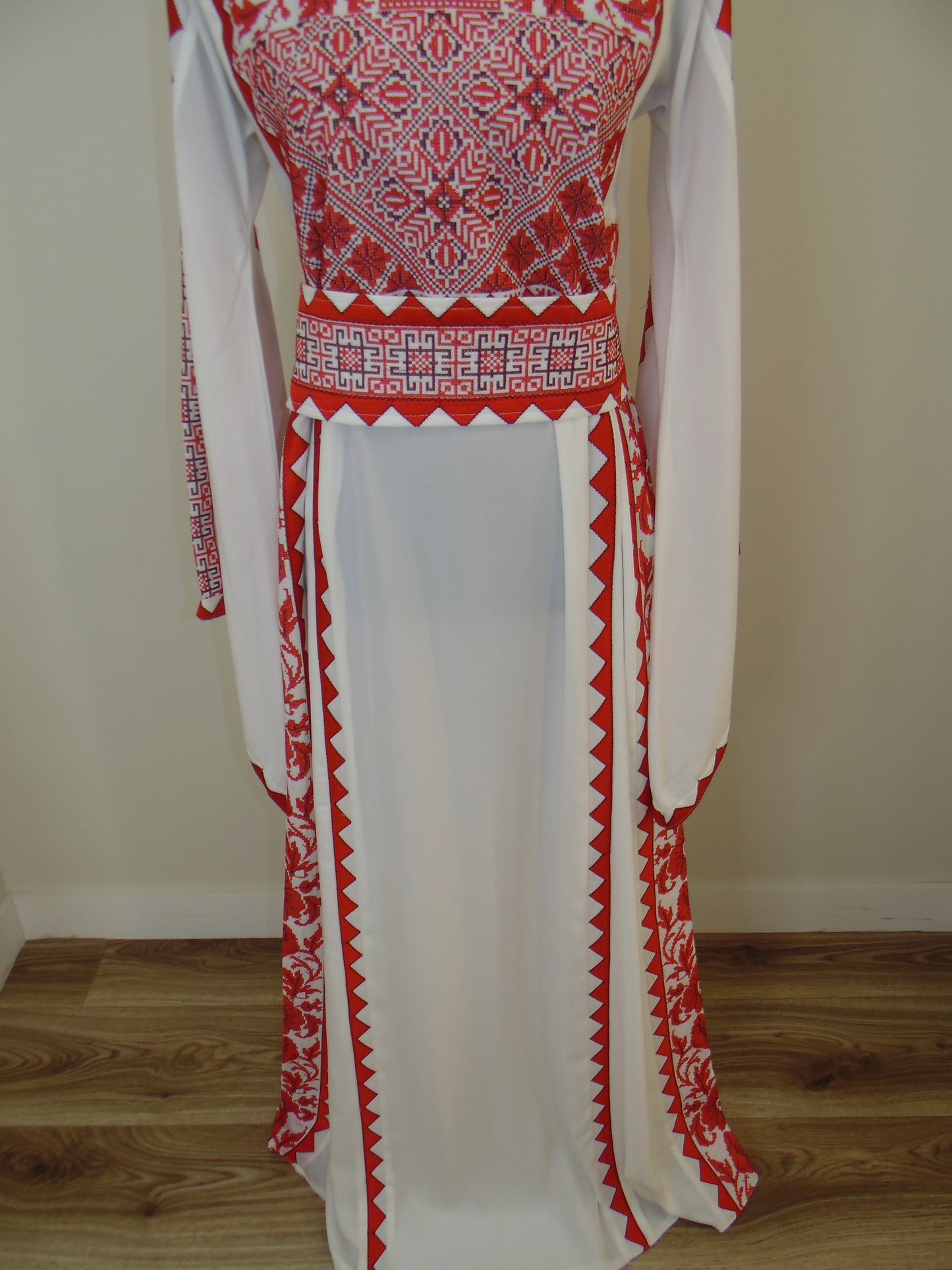 Traditional white garment with red embroidery on a wooden surface.