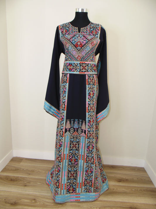 Colorful embroidered Palestinian Thobe on a white surface with wooden floor background