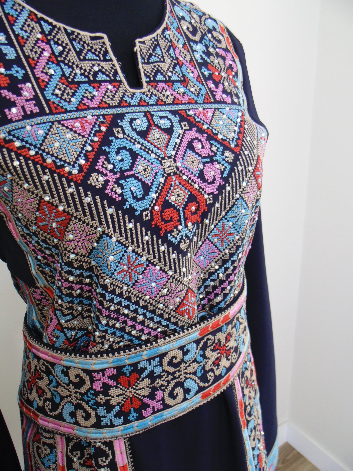 Close-up of a colorful embroidered fabric with intricate patterns on a white background