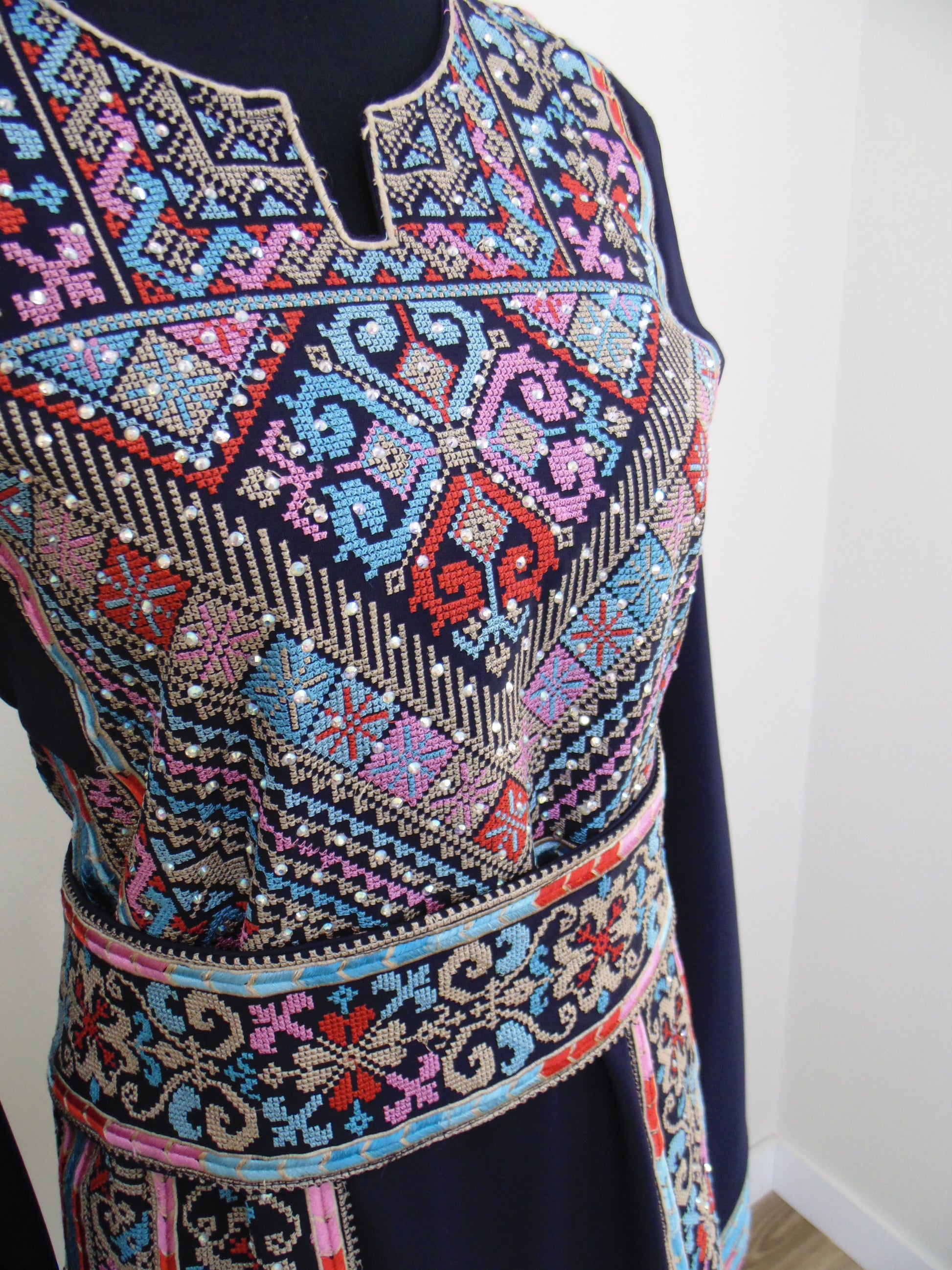 Close-up of a colorful embroidered fabric with intricate patterns on a white background