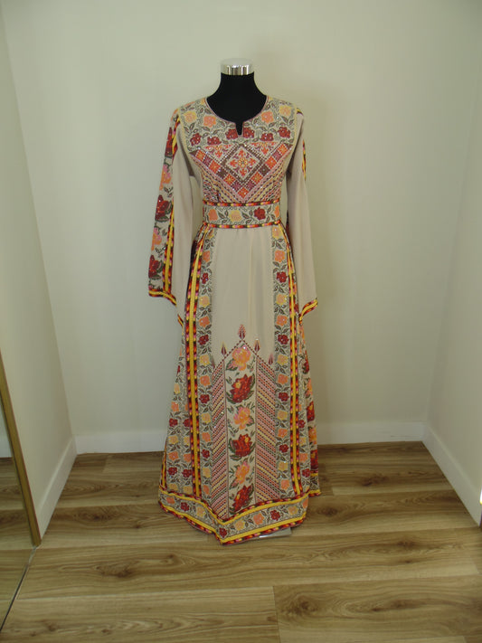 Traditional embroidered palestinian Thobe on a mannequin against a wooden wall.